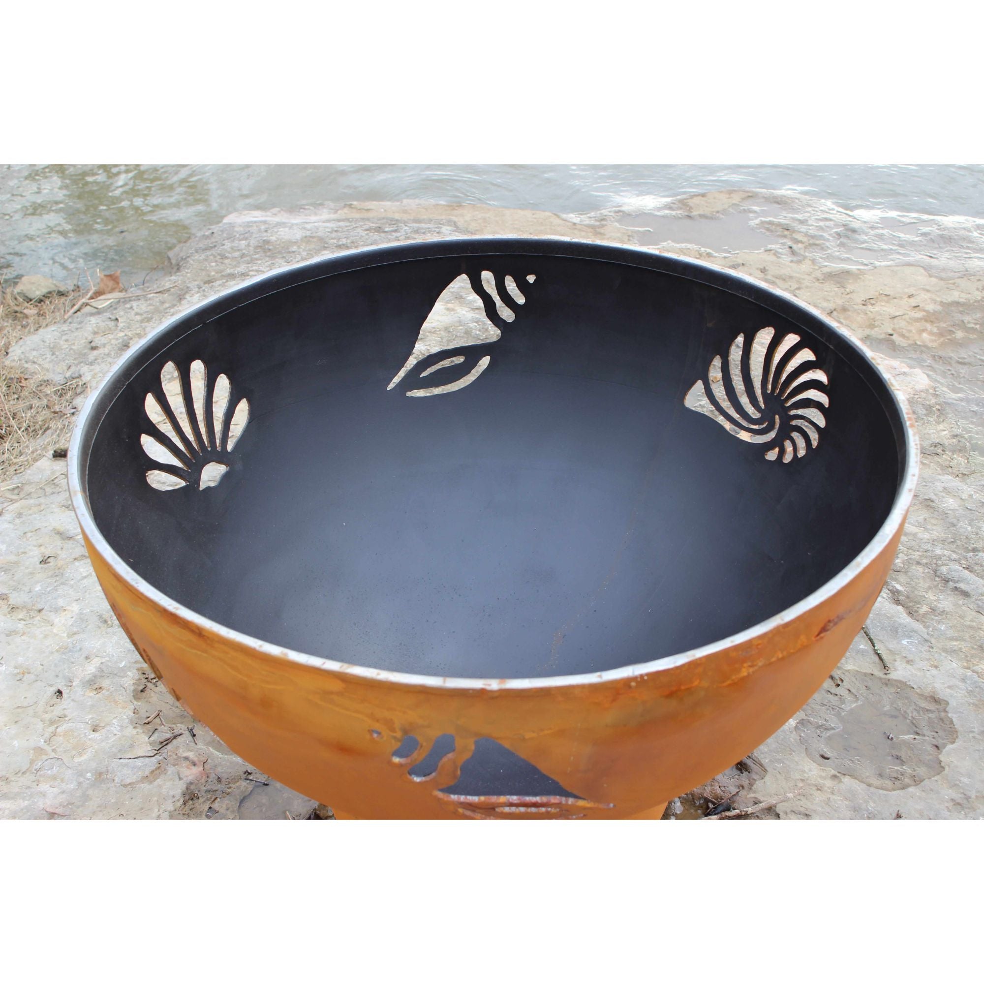 Decorative metal bowl with shell designs on a stone surface