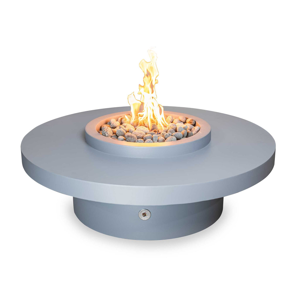 A round outdoor fire pit table with a light gray base and top platform, filled with small gray stones and lit flames, shown on a plain white background.