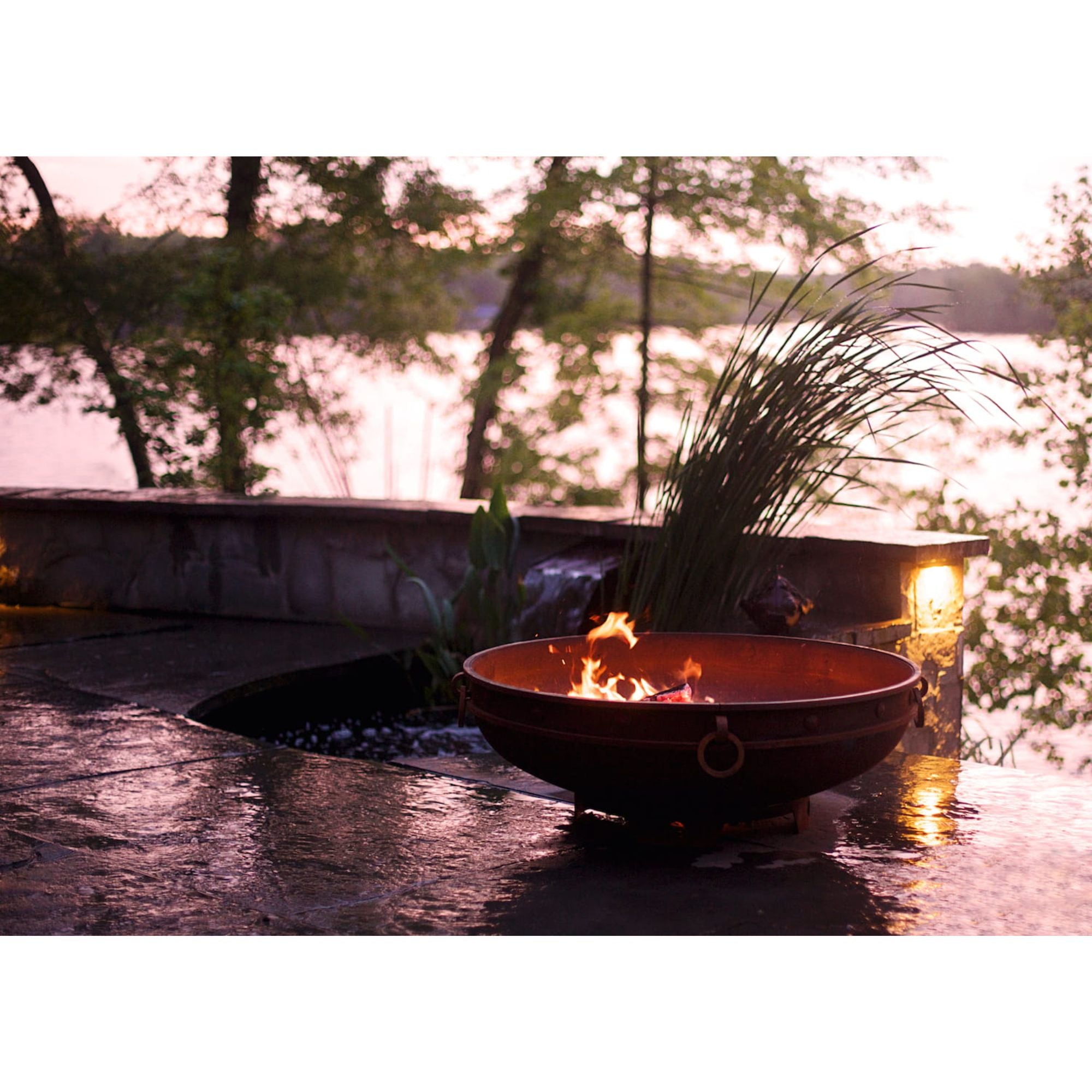 Fire pit by a lake with trees in the background