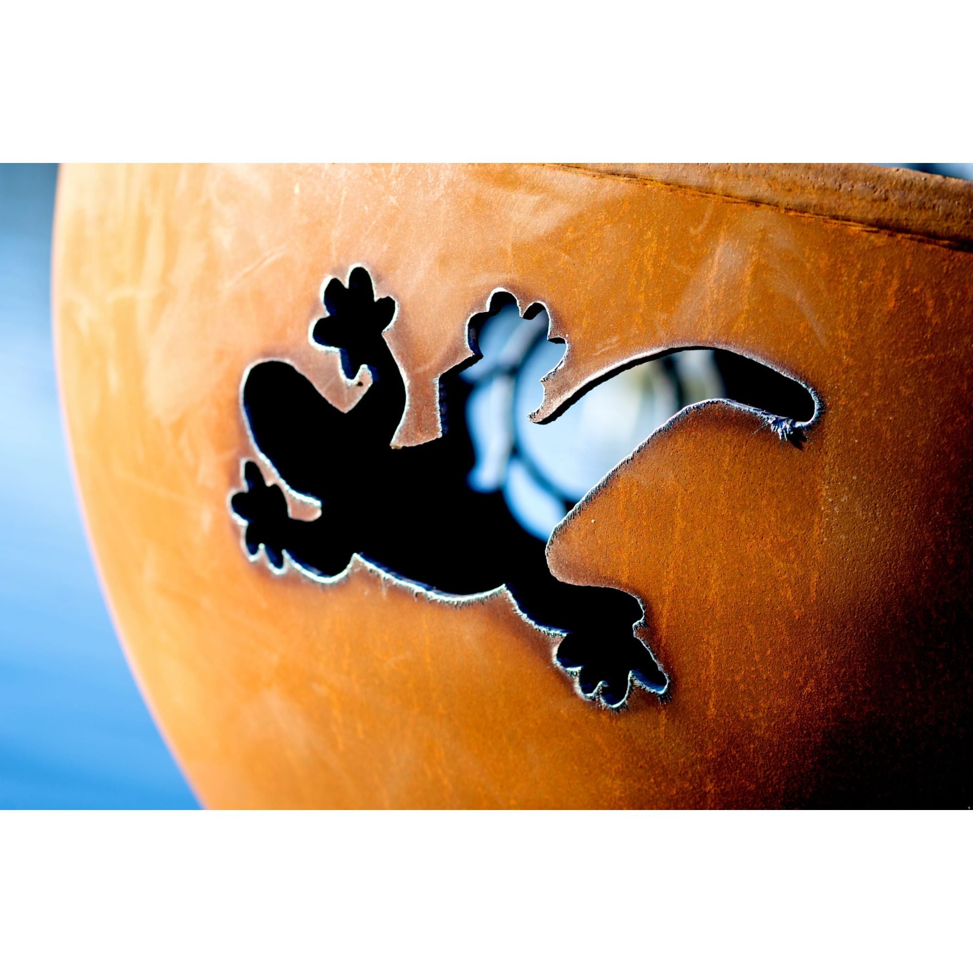 Black silhouette of a lizard on a textured orange surface with a blue gradient background