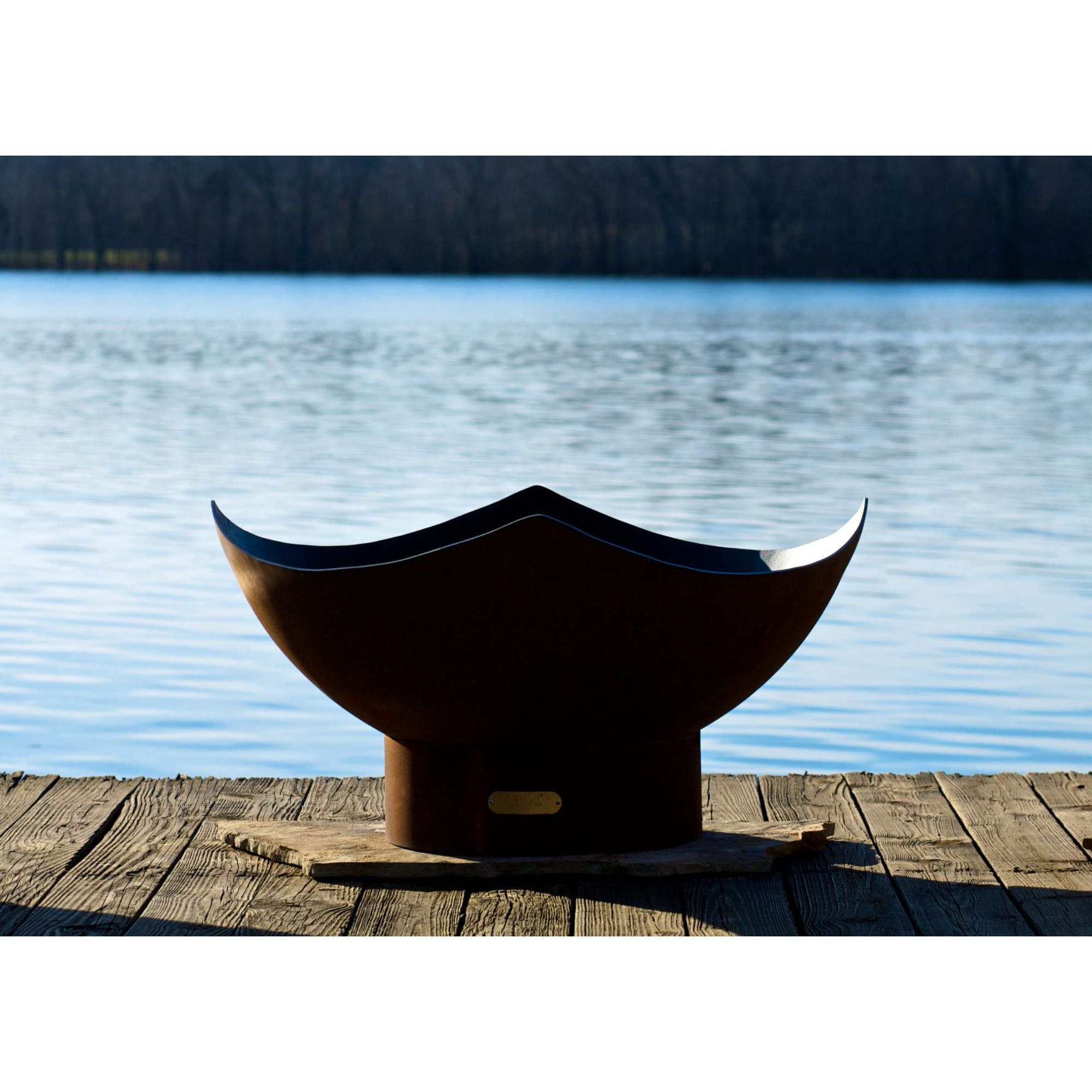 Black metal bowl on a wooden dock by a lake