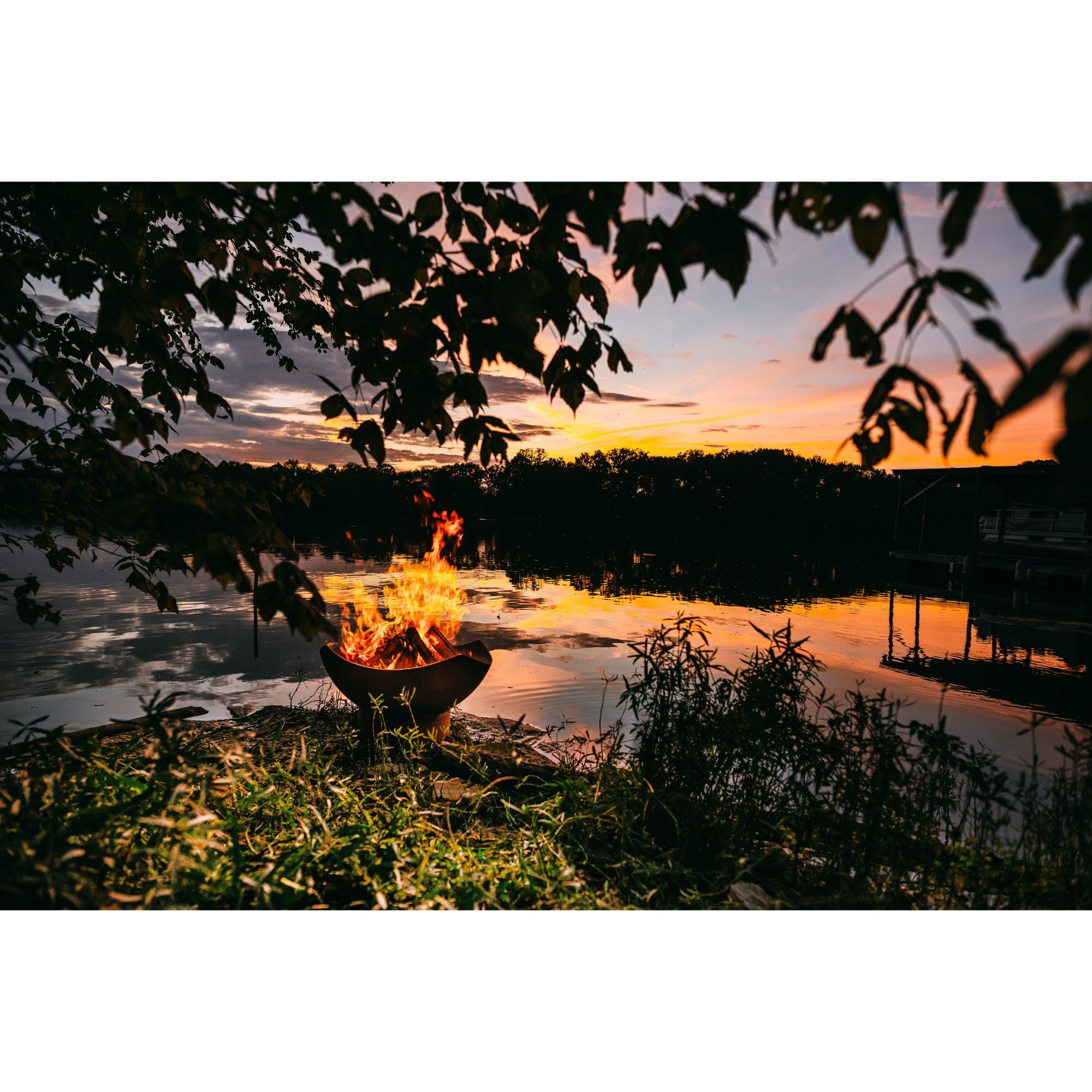 Fire pit by a lake at sunset with trees and water in the background