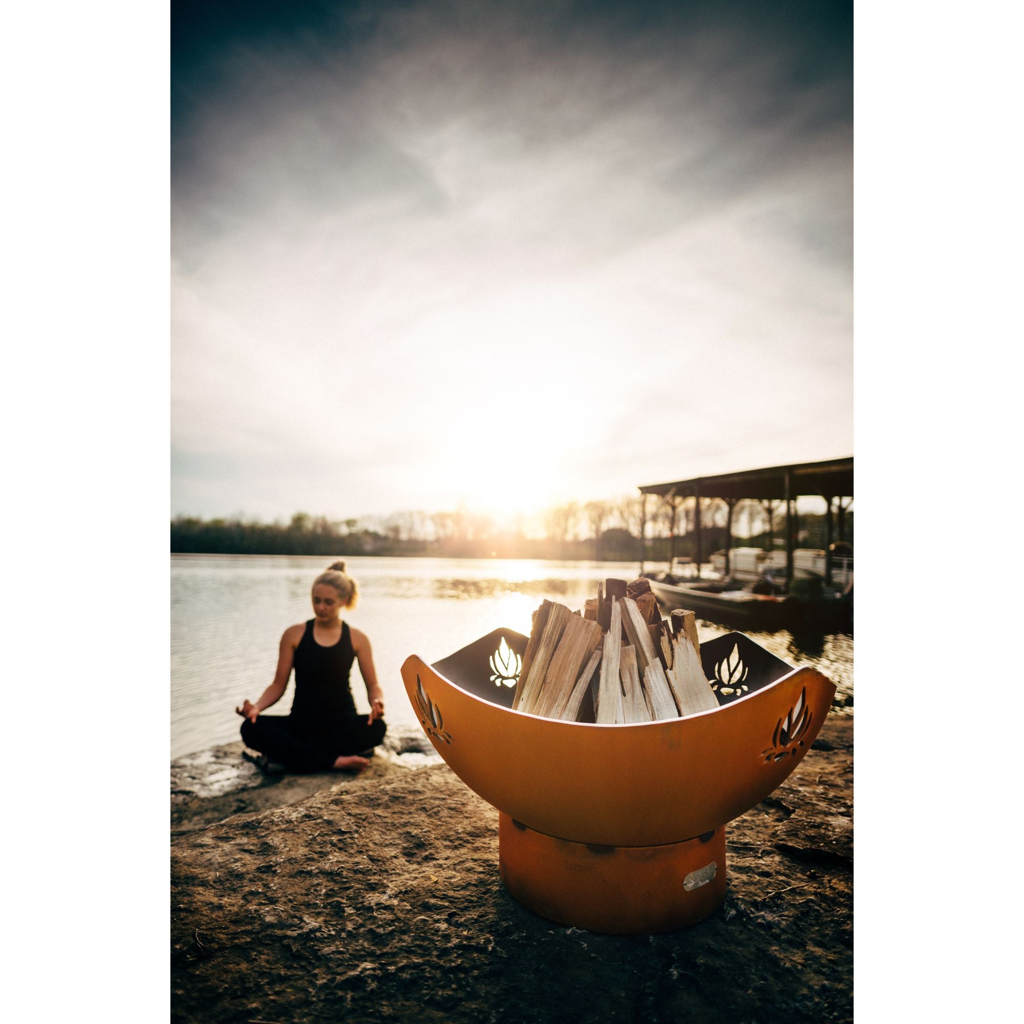 Fire pit by a lake at sunset with trees and water in the background
