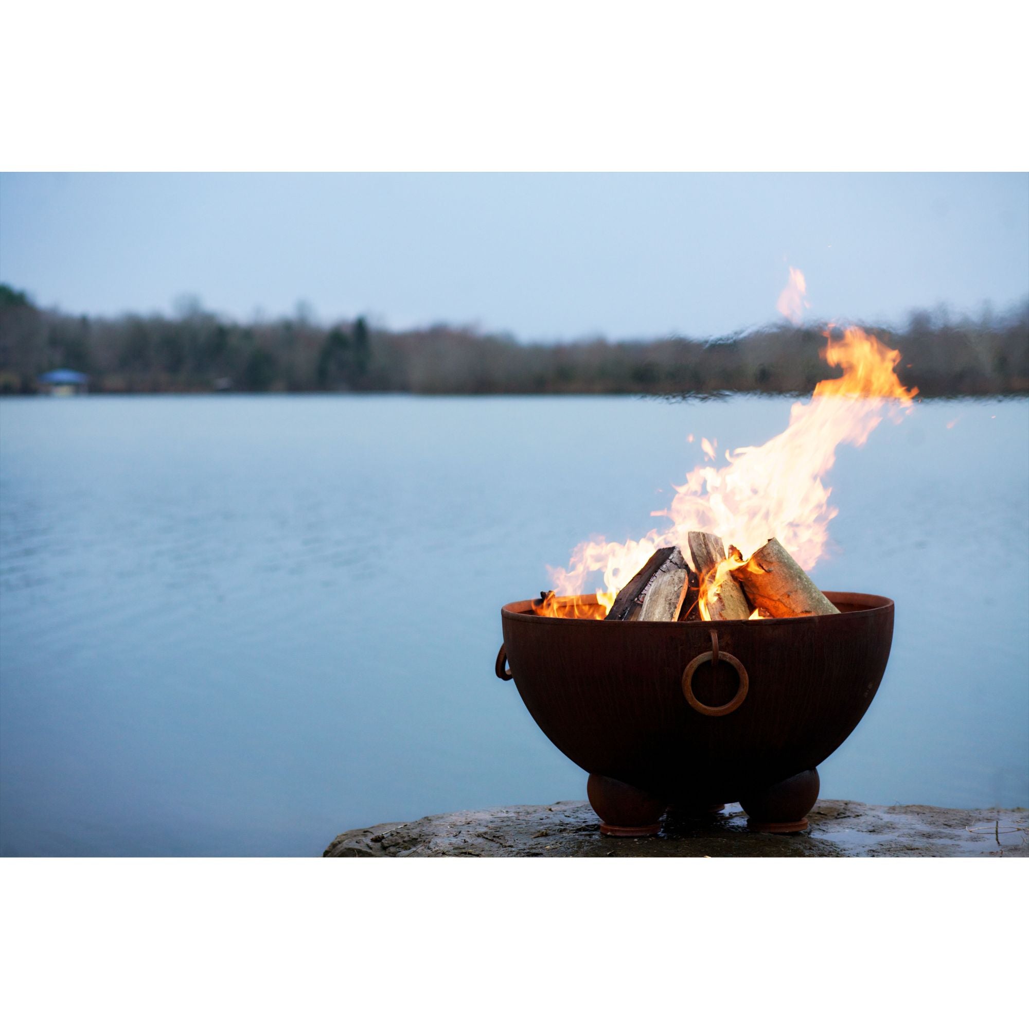 Fire pit with flames burning near a body of water