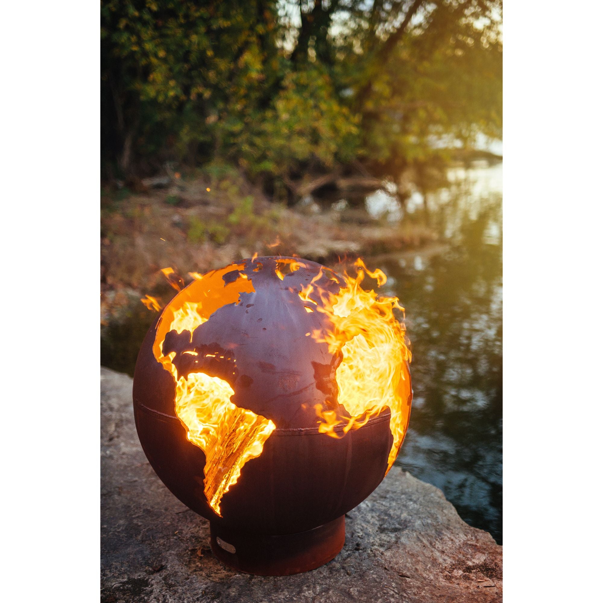 fire pit with flames standing on a rock by the ocean with blurred out trees in the background