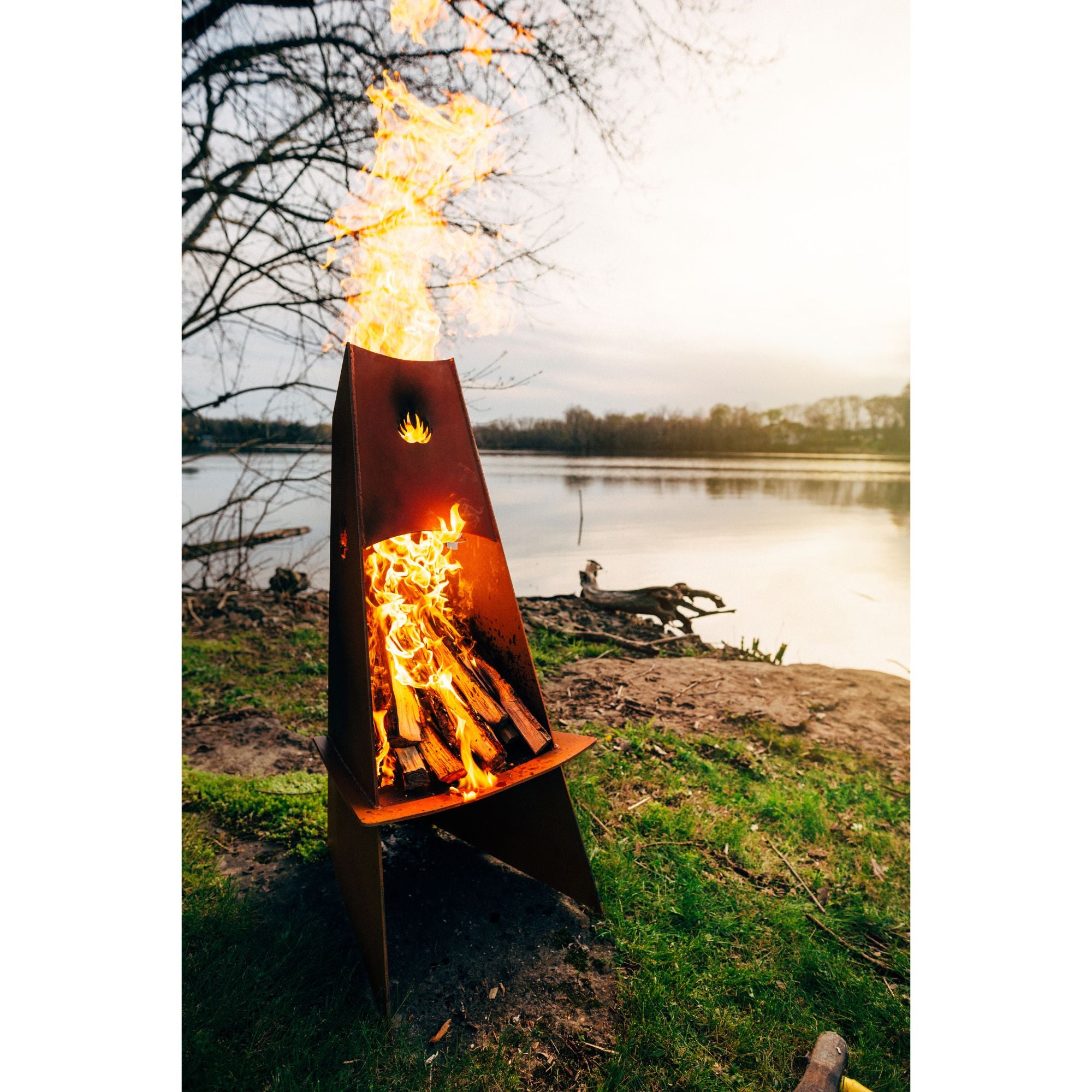 Fire pit with flames lit up outdoors by a lake