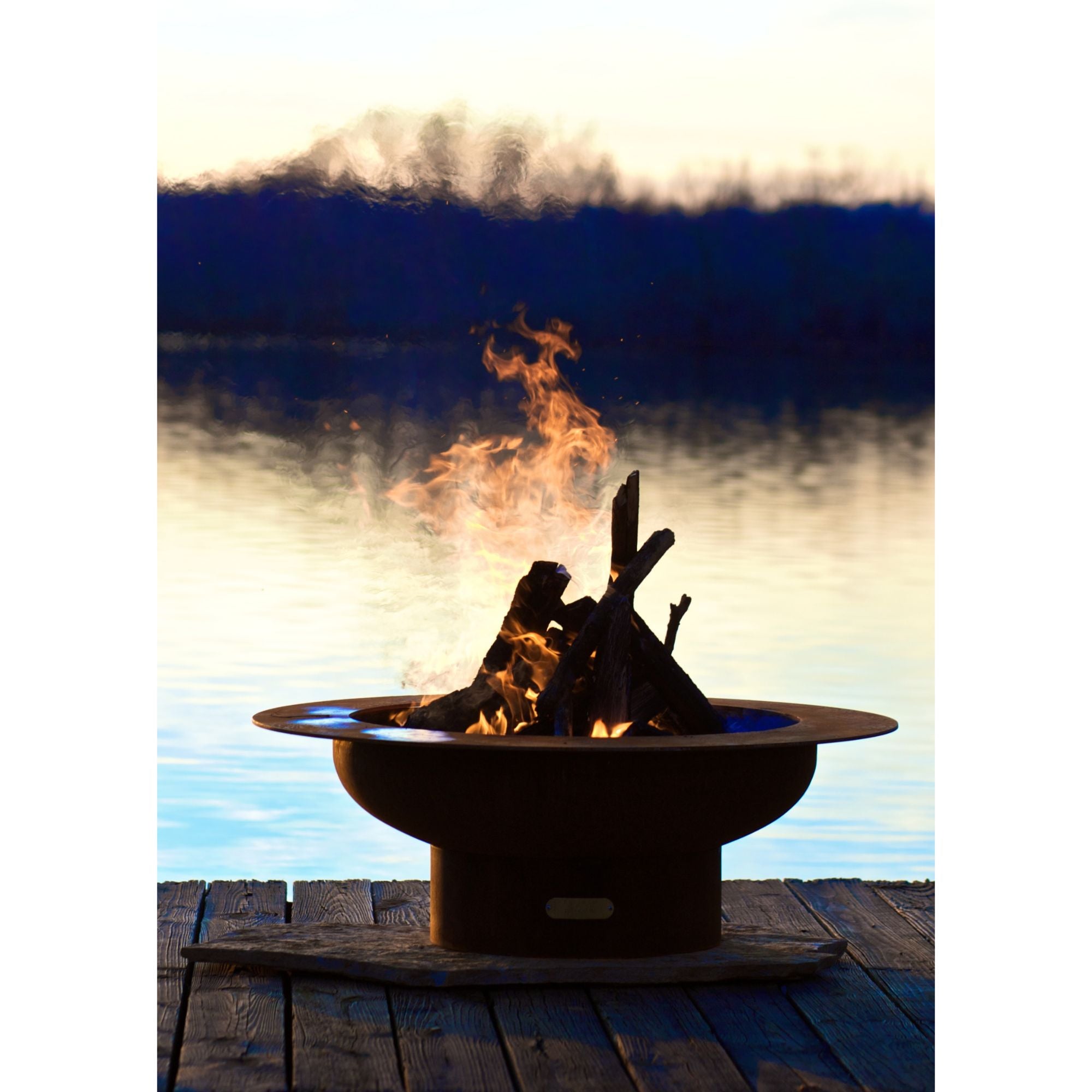 Fire pit with flames against a lake sunset