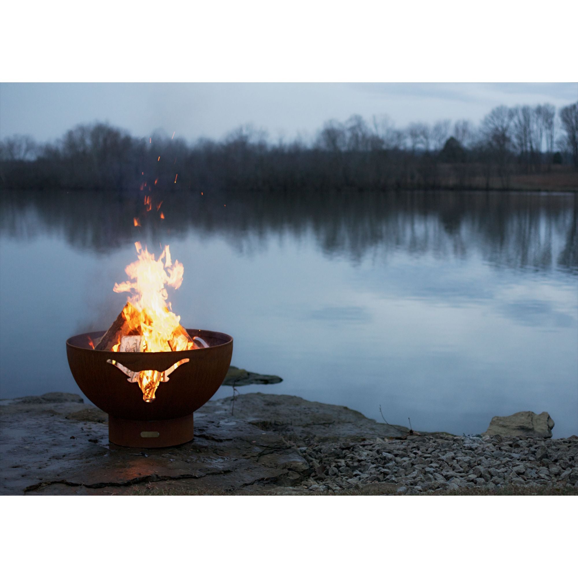 Fire pit by a lake with flames burning brightly