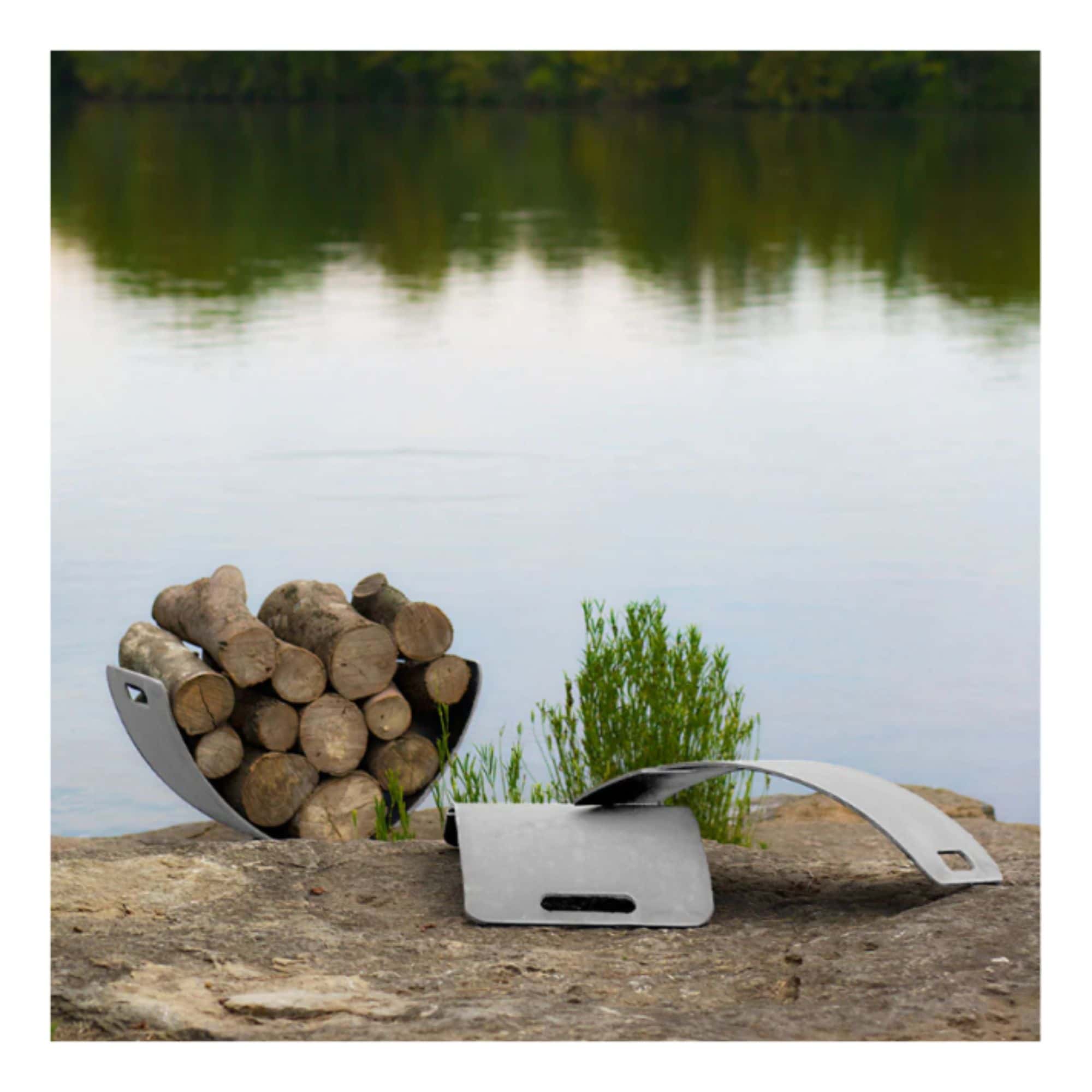 Wooden logs in a steel log rack holder with a plant on a rock surface by a body of water.