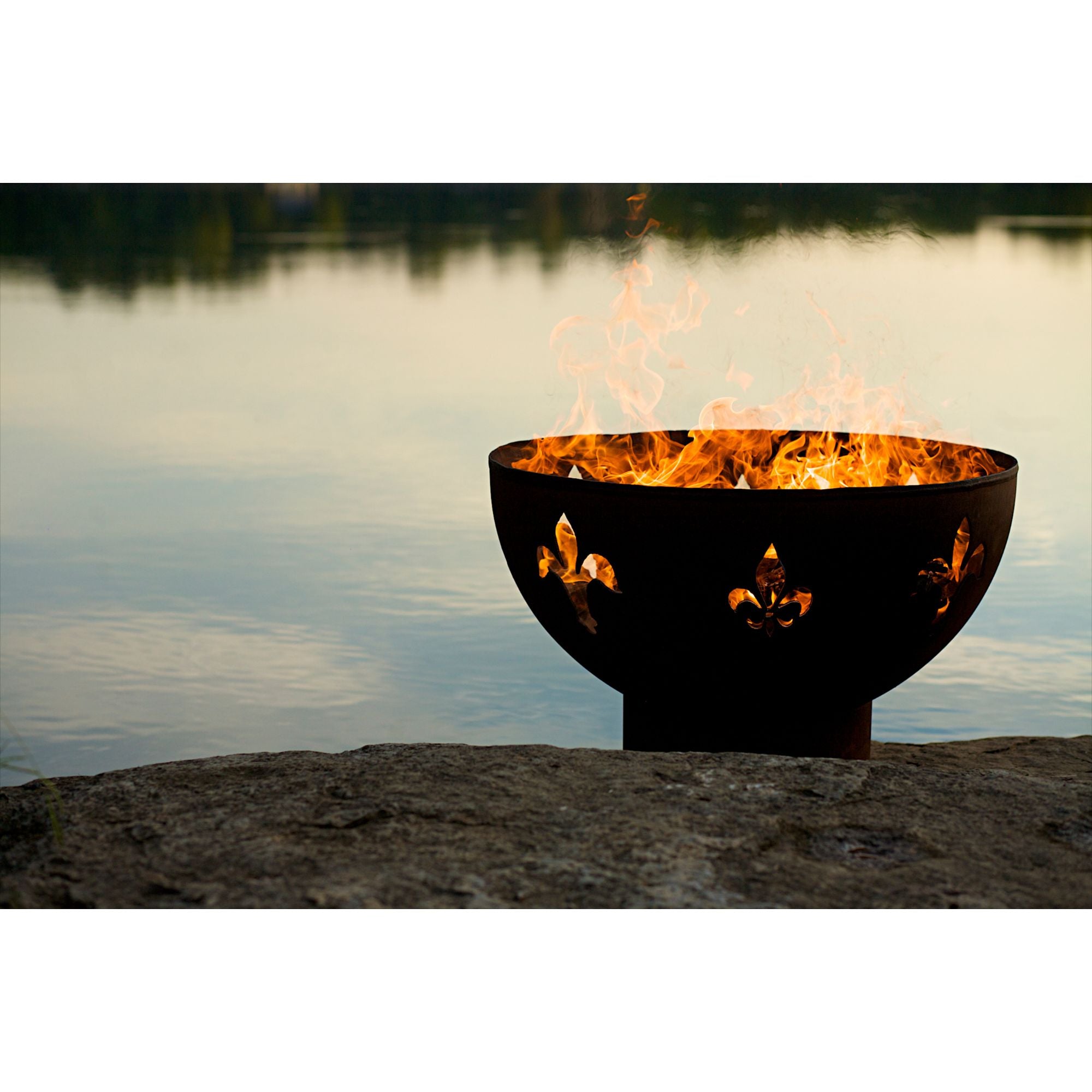 Fire pit with flames burning in front of a lake