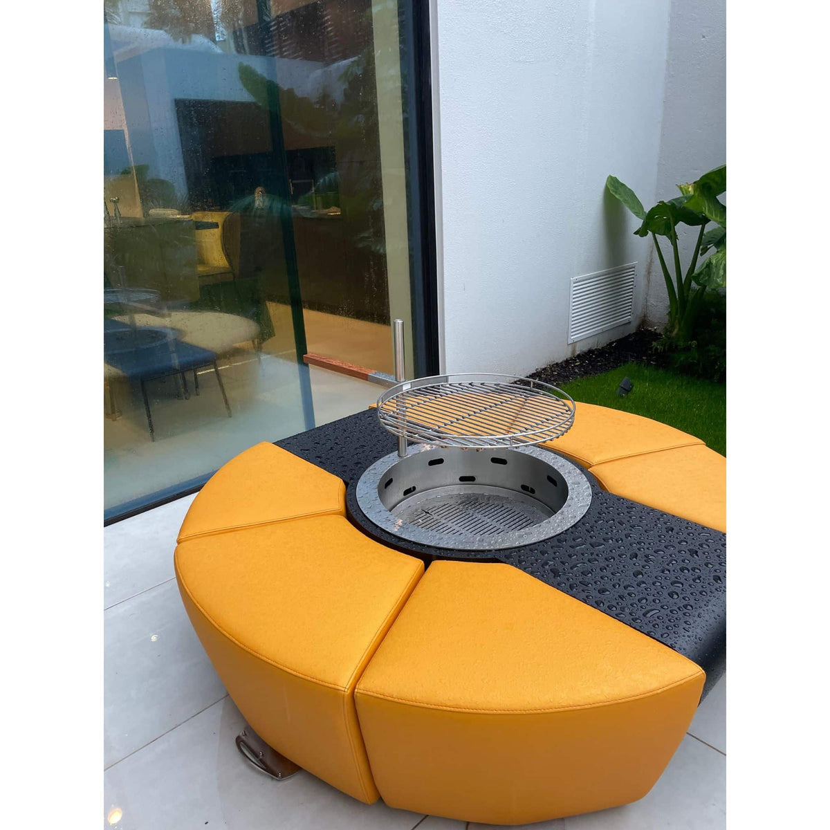Modern outdoor seating area with yellow cushioned bench and fire pit table.