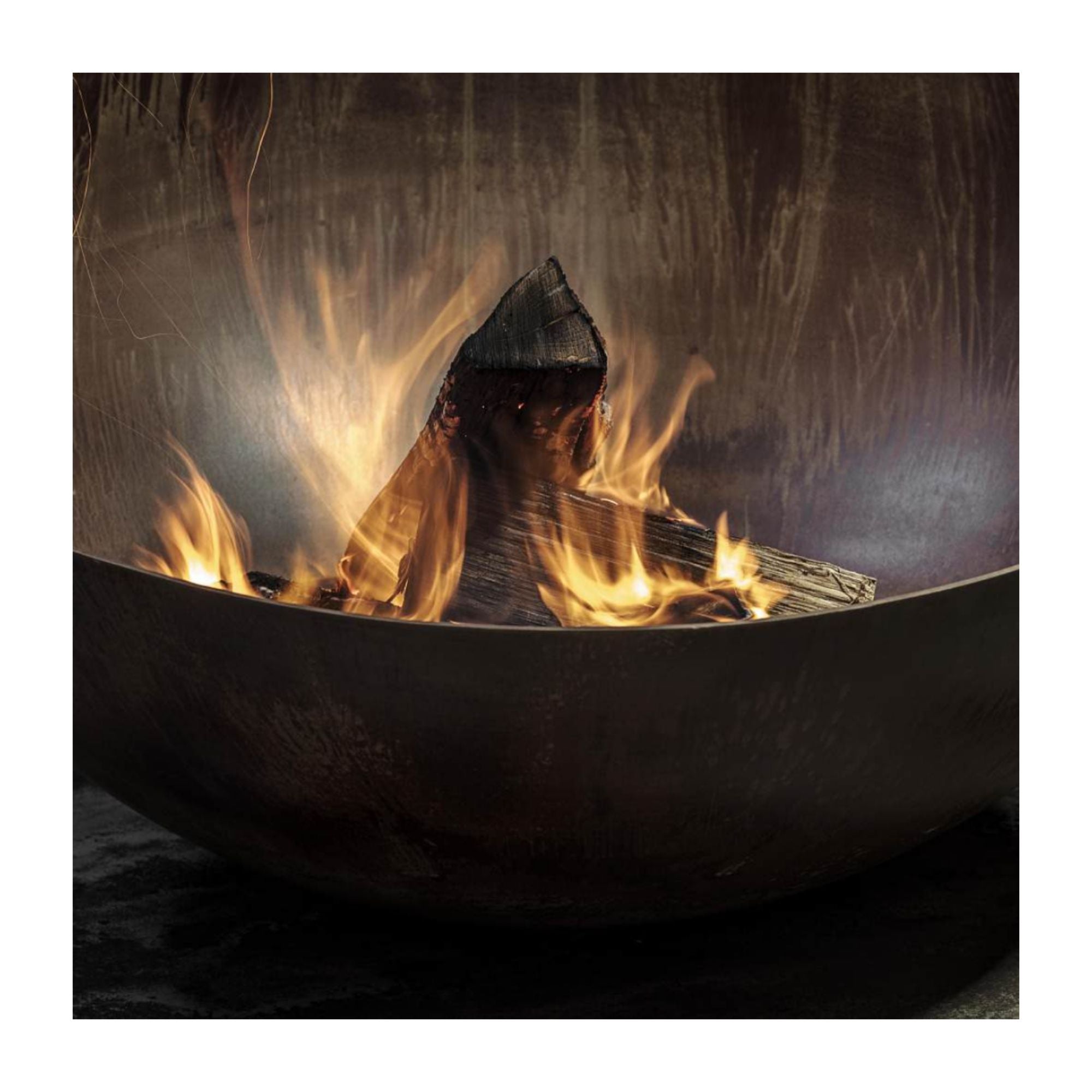 Close up of a rusted steel fire pit with flames