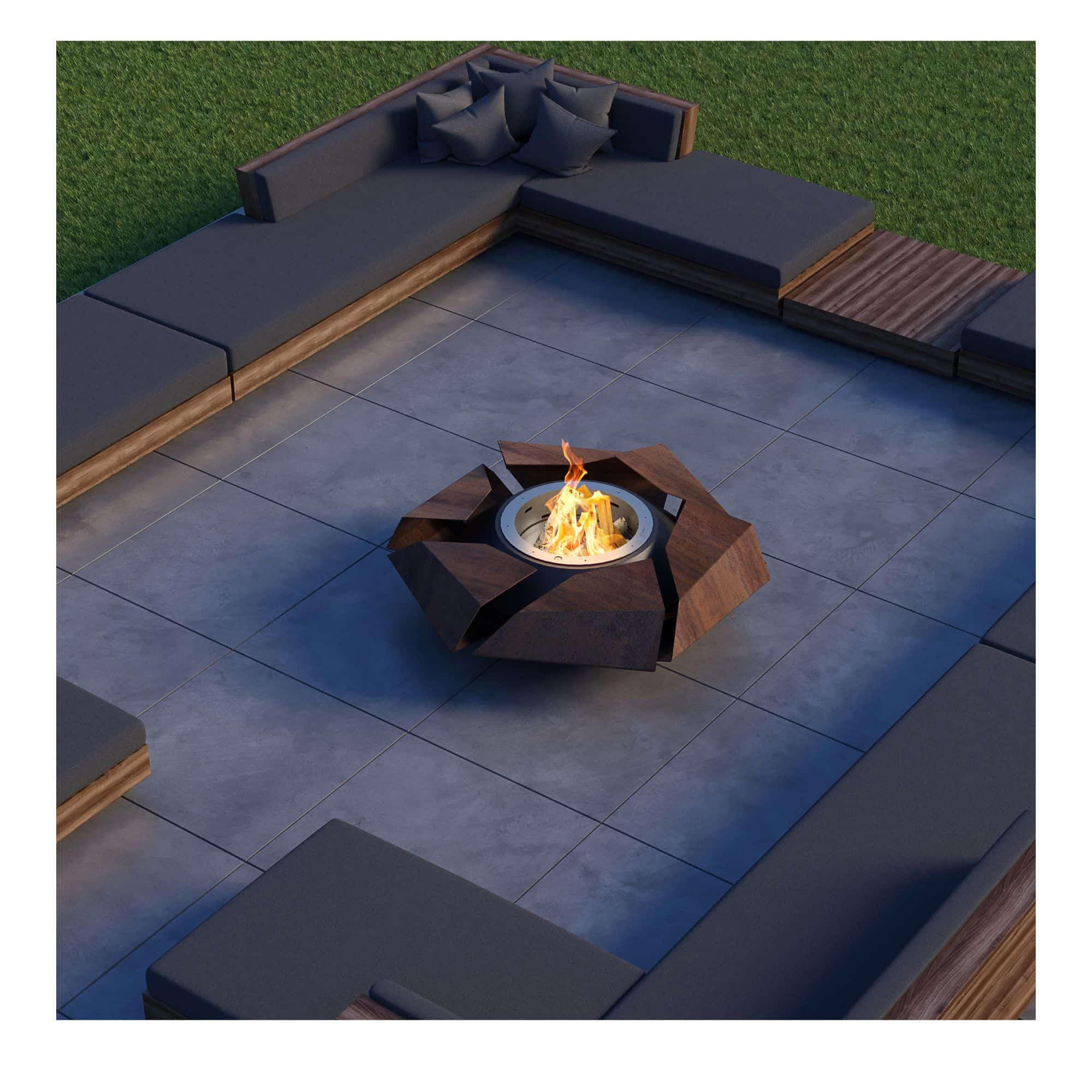 firepit with flames burning in the evening. The firepit is placed in a backyard setting with sofas surrounding it.