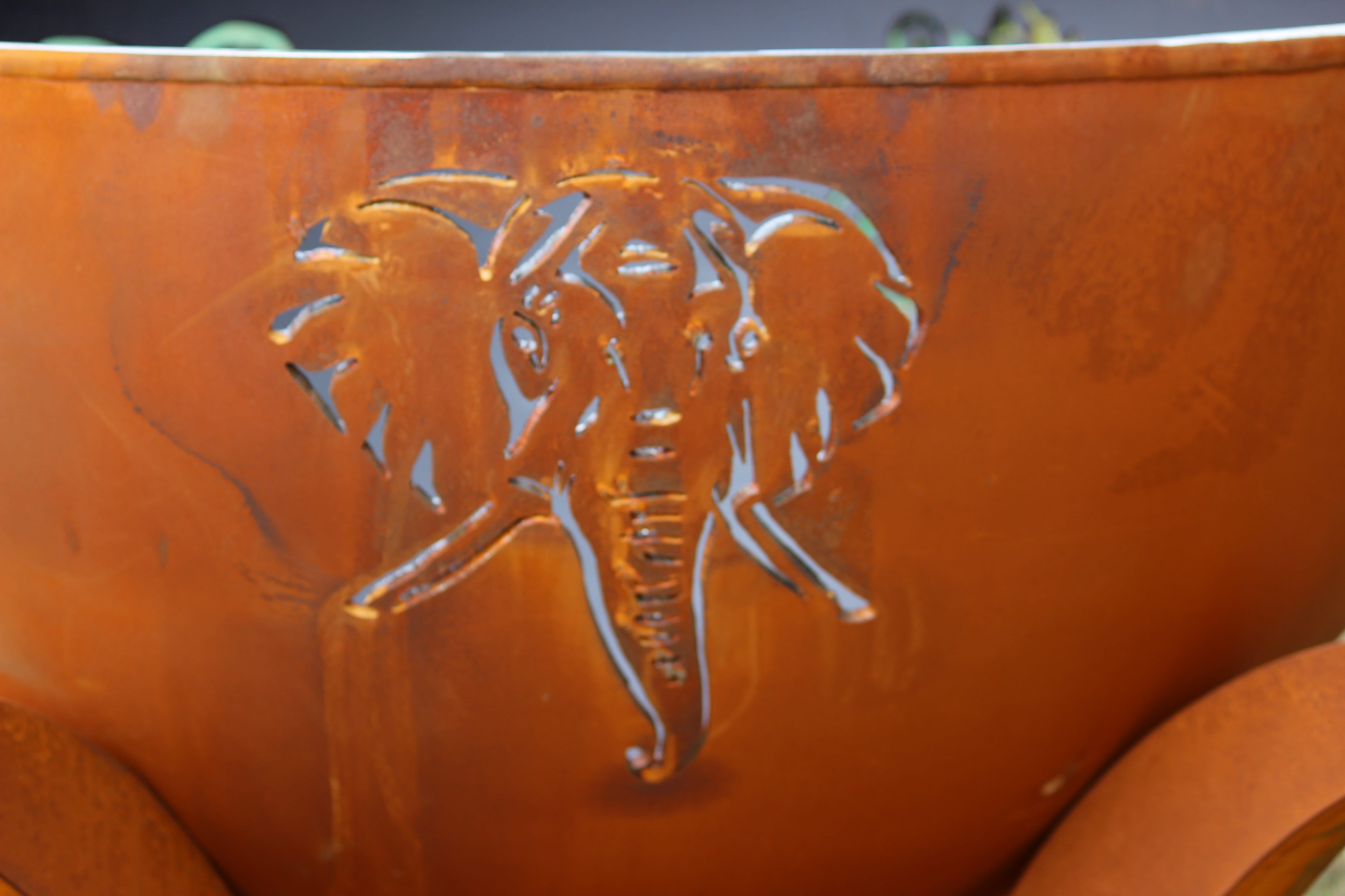 carbon steel fire pit with an elephant design on a brown background