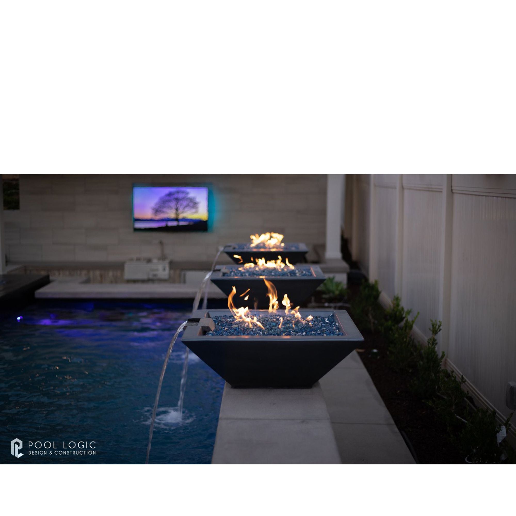 Outdoor fire pit area with water feature and television screen in the background
