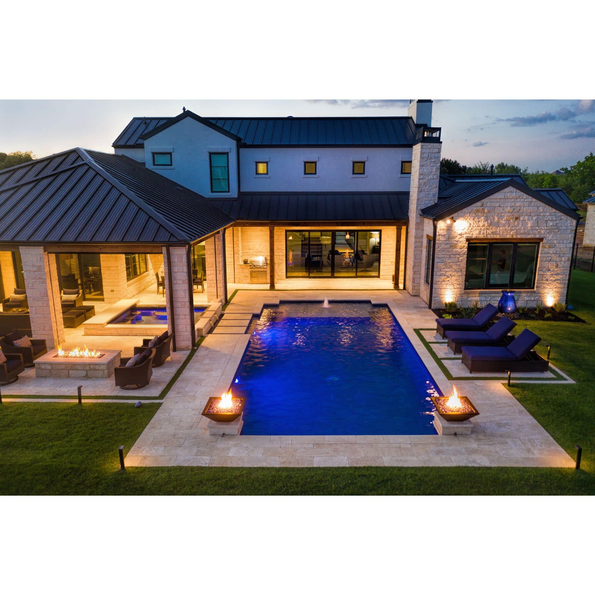 two fire bowls with flames by a pool in the evening