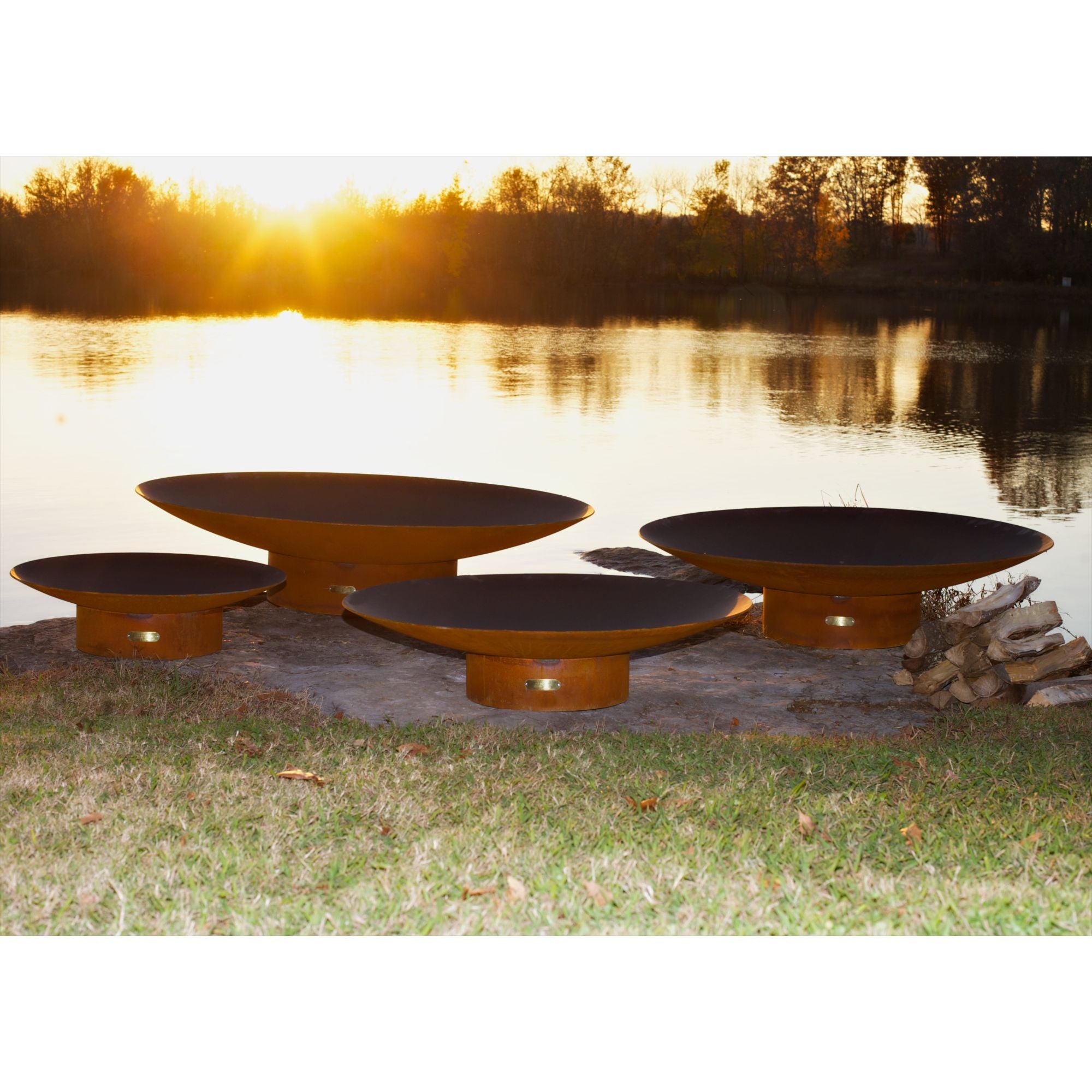 Four round steel fire pits by a lake at sunset