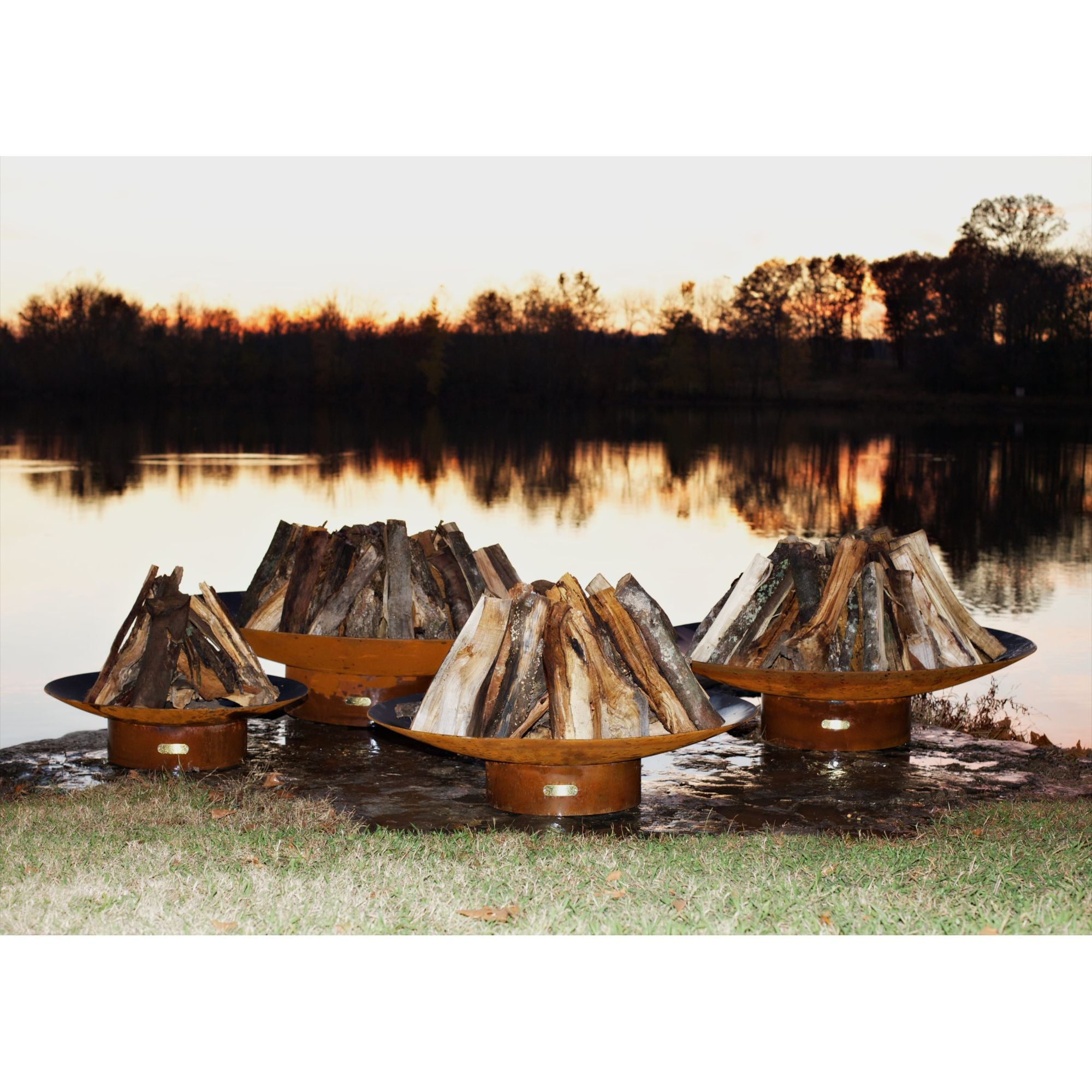 Four wooden fire pits arranged around a lake at sunset.