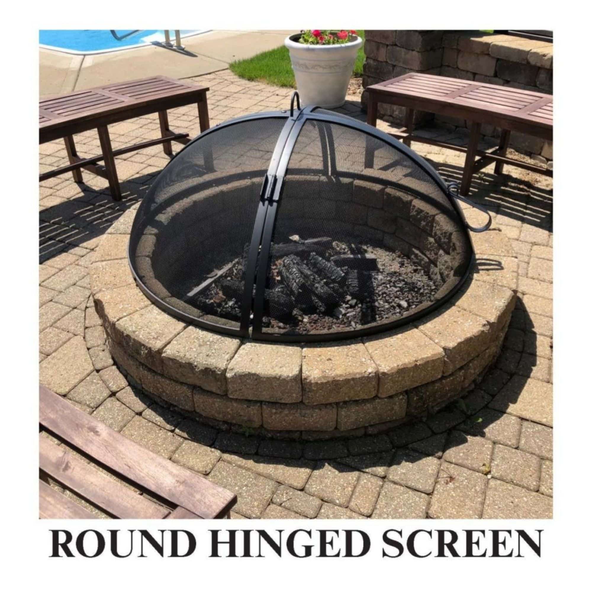 Round fire pit with a black metal mesh screen cover, shown outdoors on a paved patio with benches and a pool in the background. Text at the bottom reads 'ROUND HINGED SCREEN'.