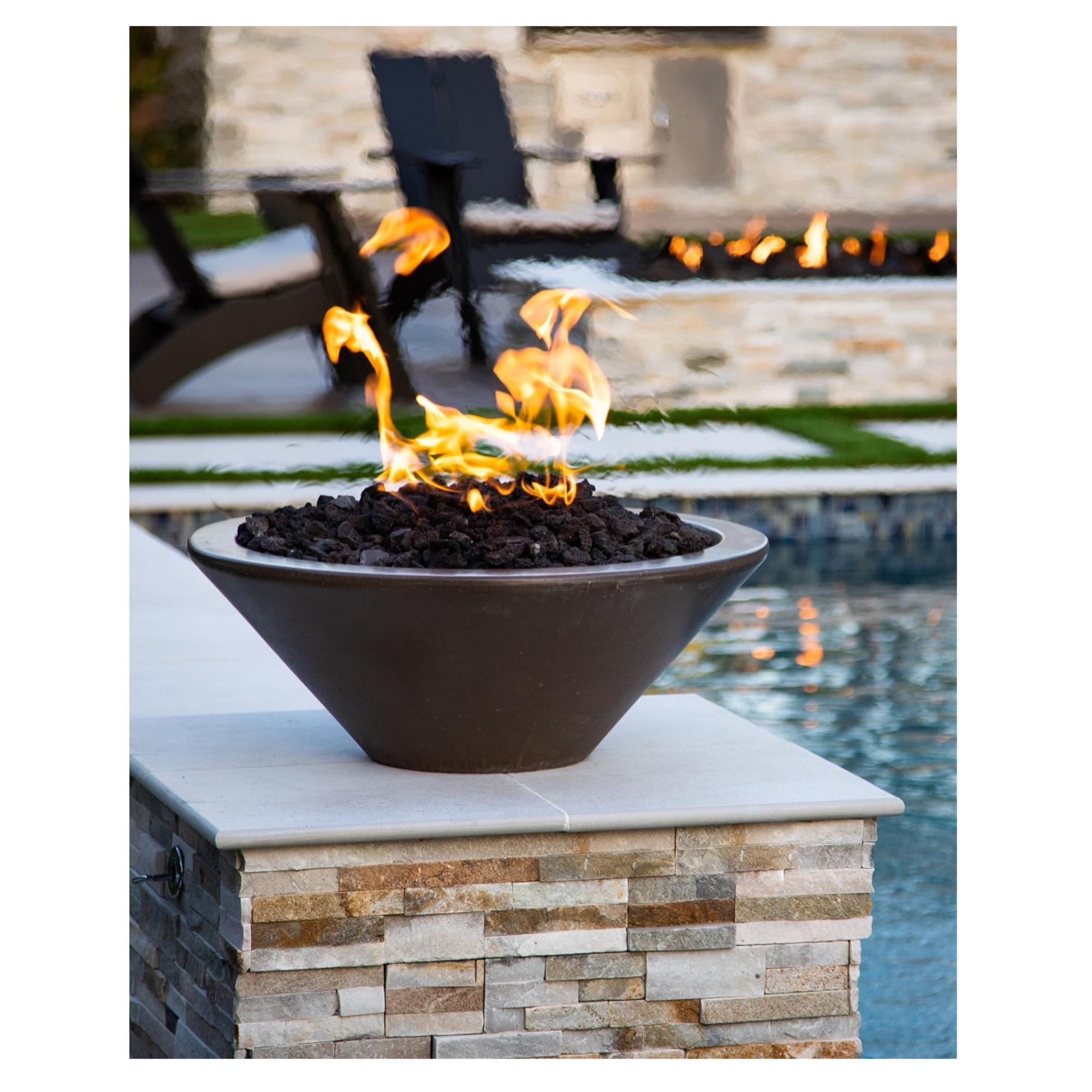 Fire pit with flames on a stone platform by a pool