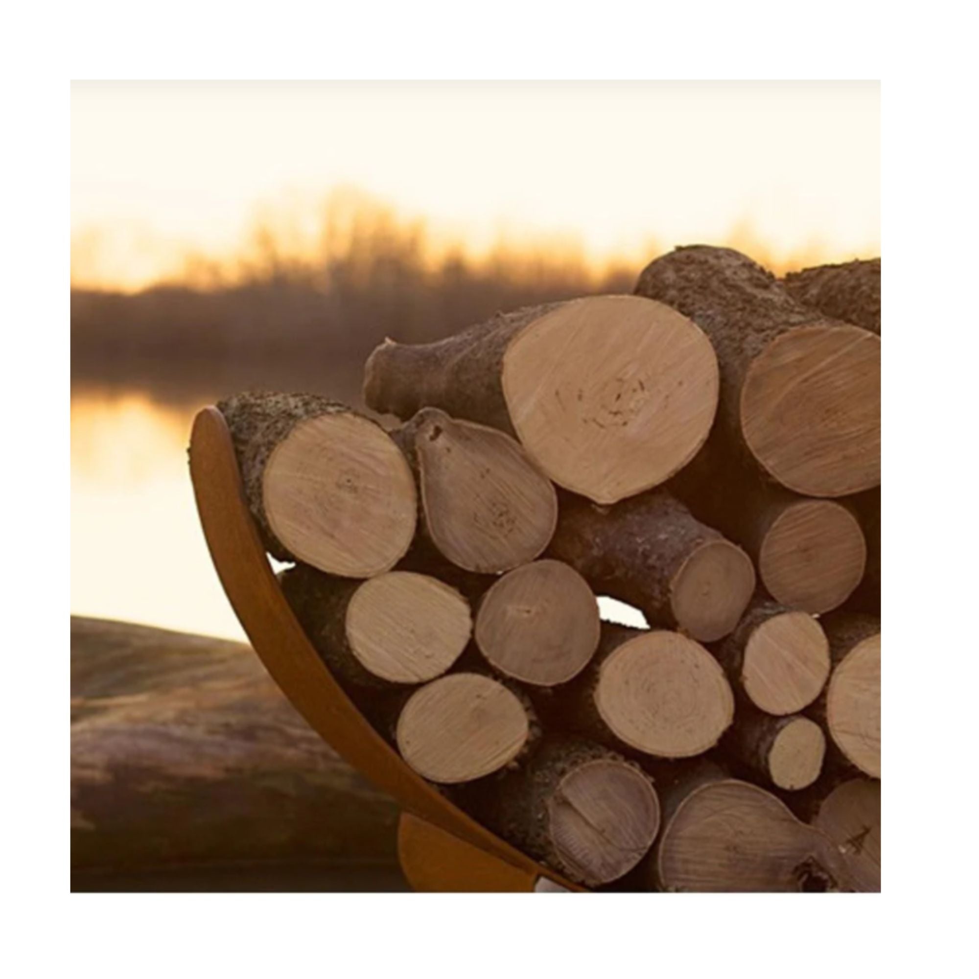 Stack of logs with a sunset or sunrise over water in the background