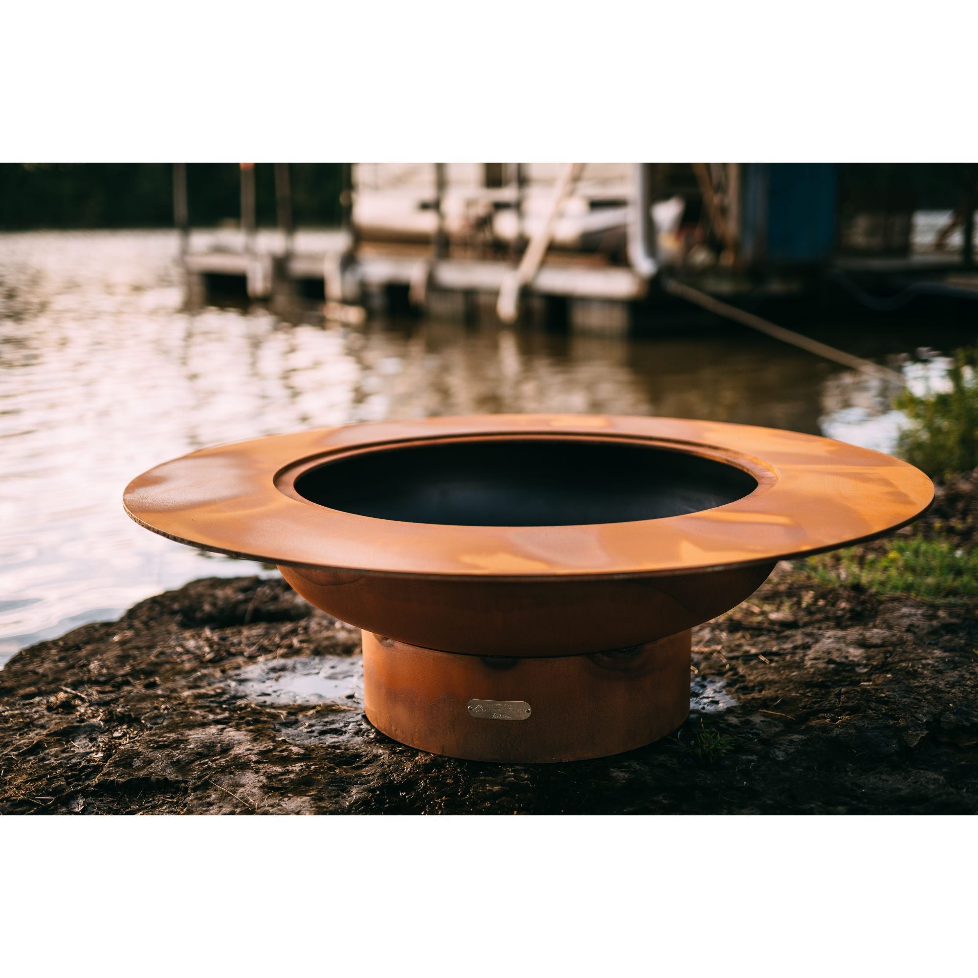 Copper fire pit on a lakeside dock with boats in the background