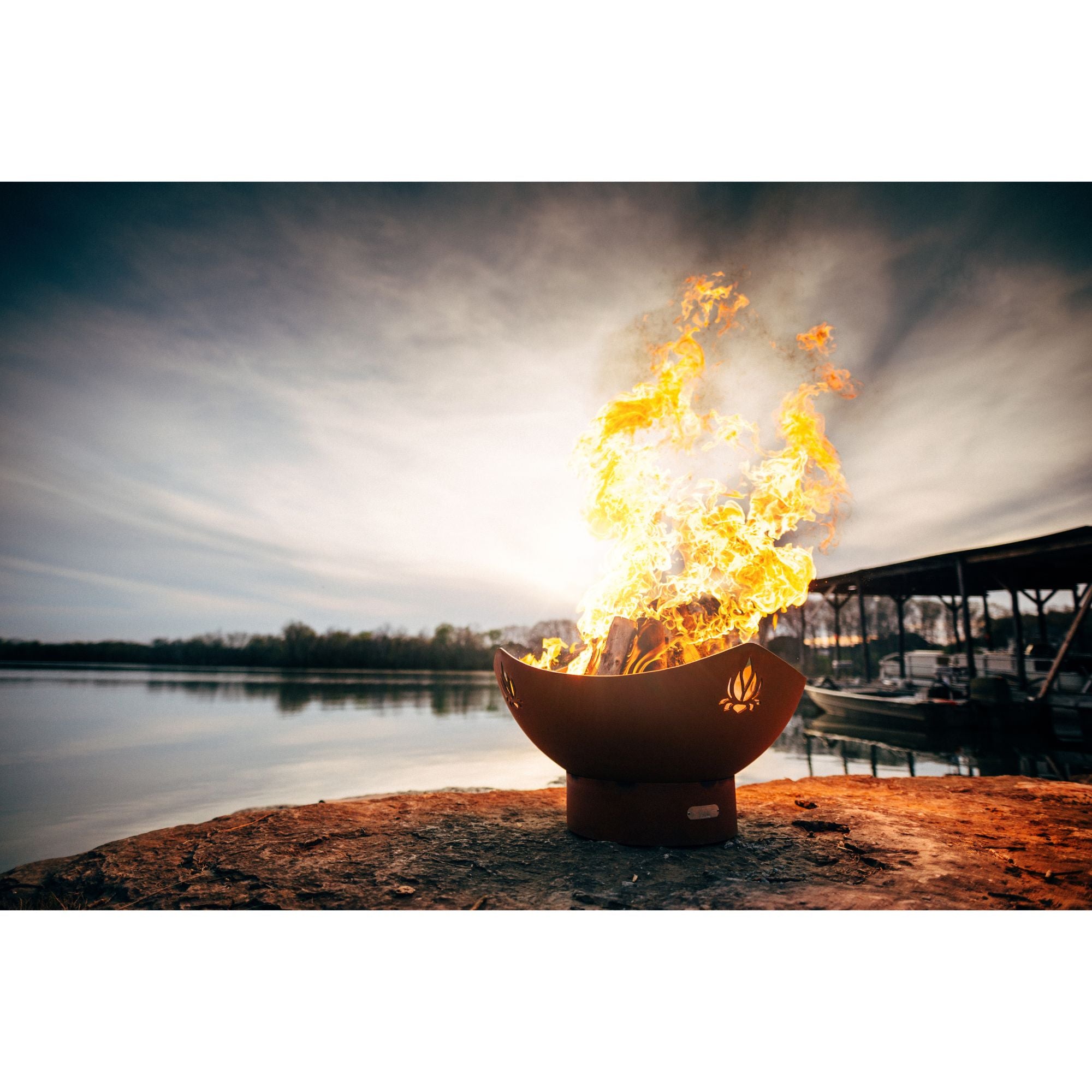 Fire pit with flames burning brightly by a lake