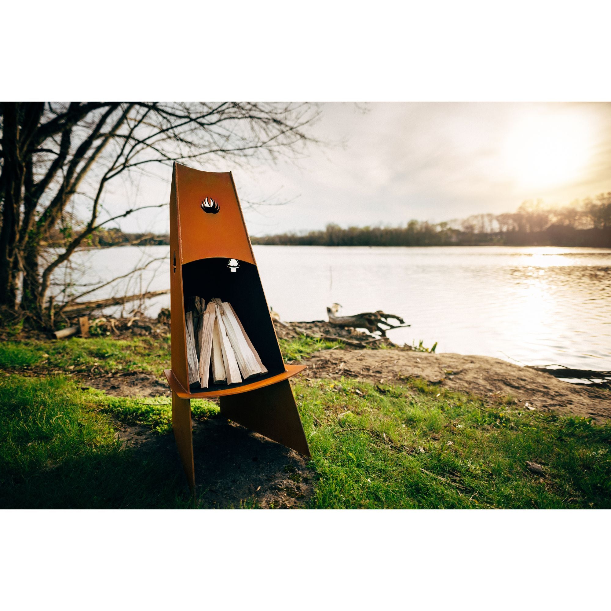 Wooden fire pit with kindling by a lake during sunset