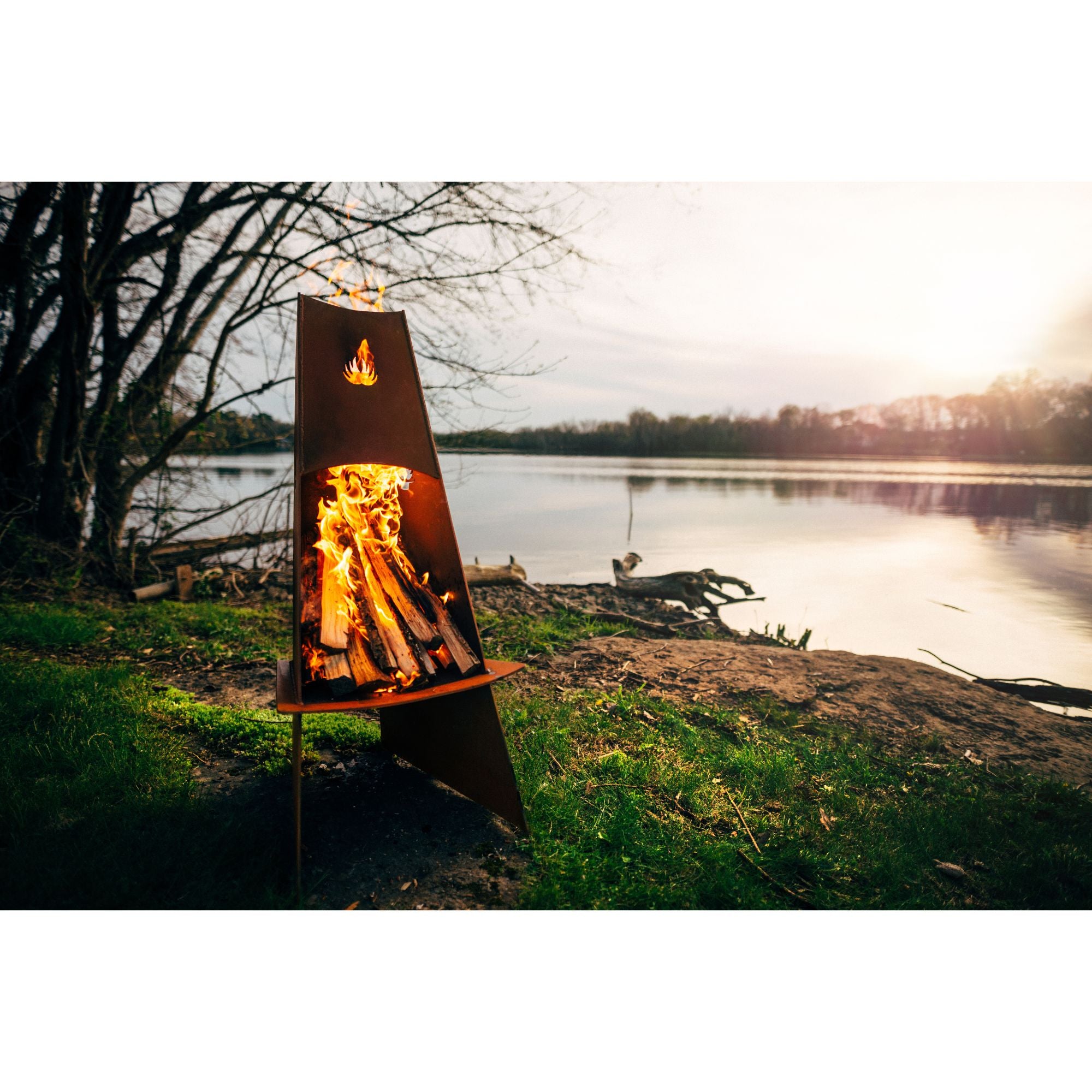 Fire pit with flames glowing in a natural setting by a lake