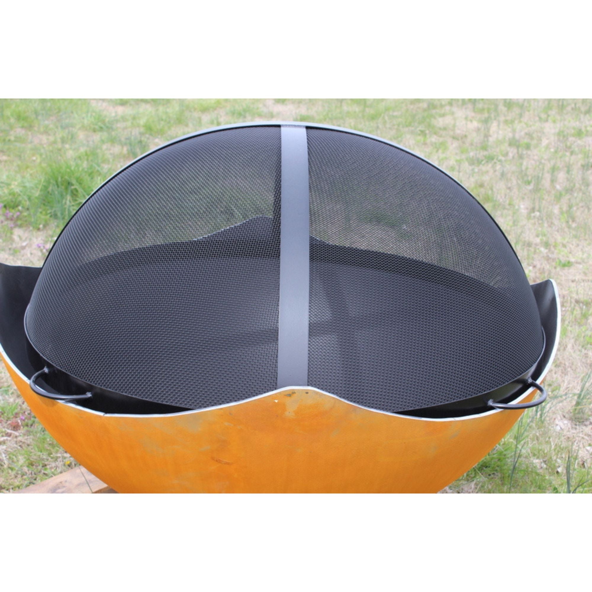 Black fire pit spark guard on a grassy background