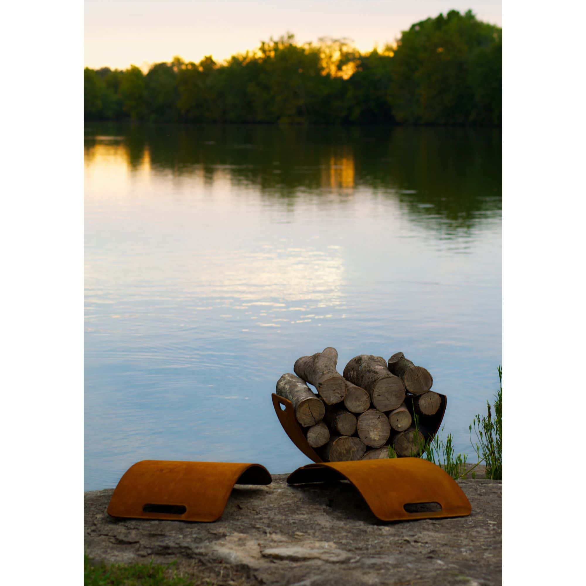 steel log rack with logs by a lake at sunset