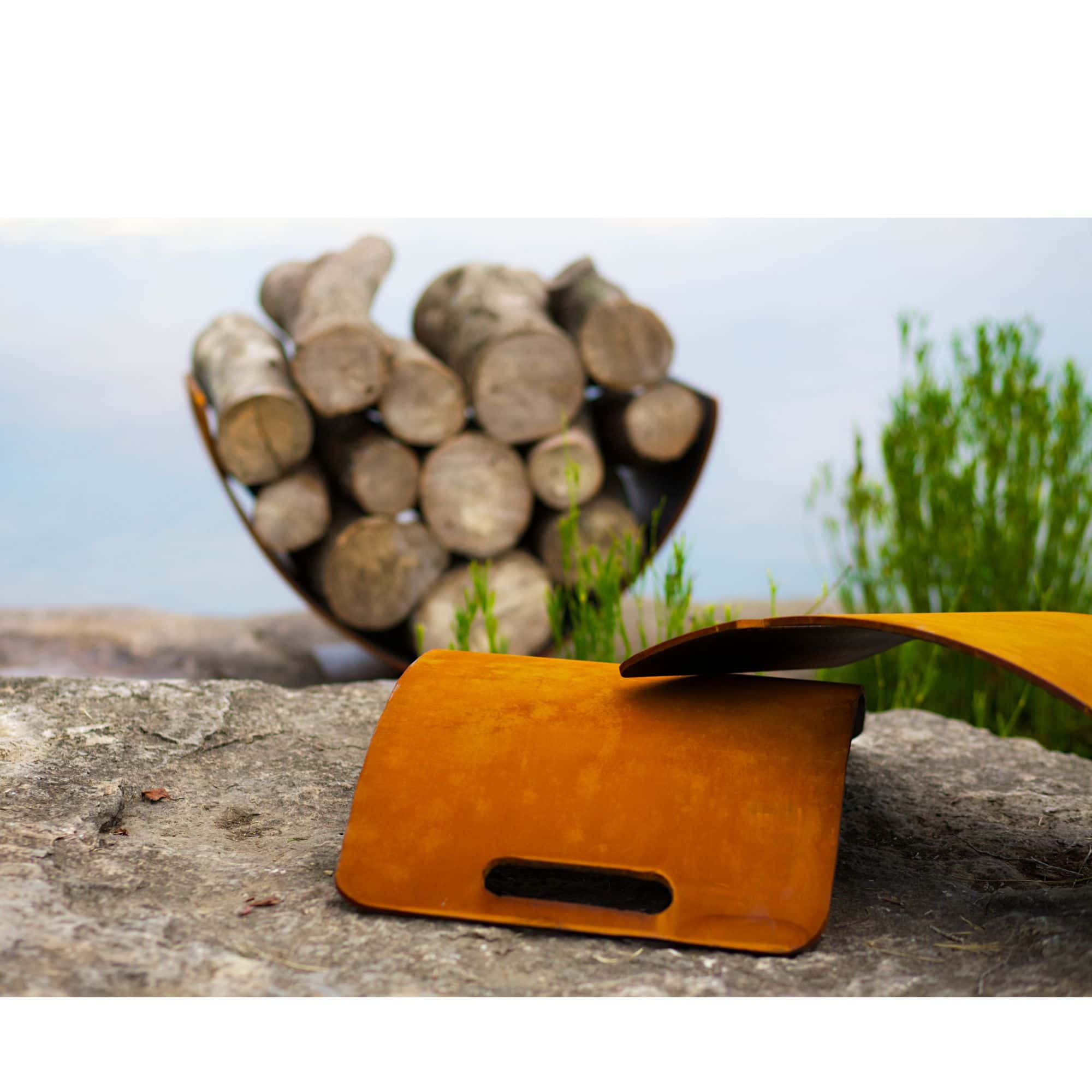 Orange log rack on a rock with stacked logs and greenery in the background