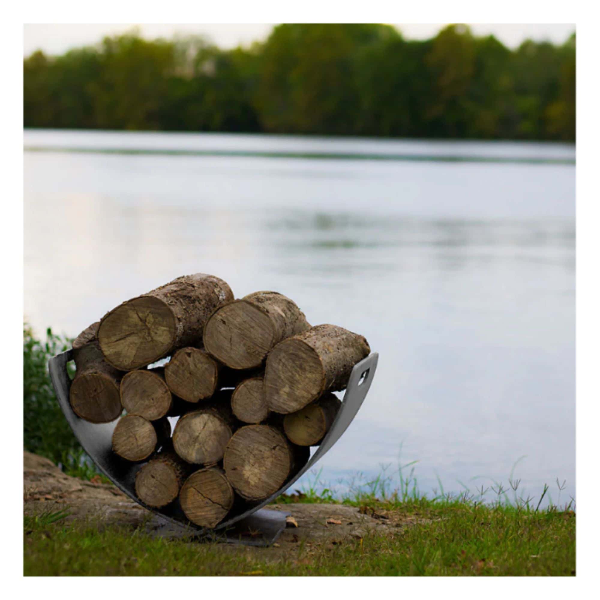 Stack of firewood in a steel log rack  with a lake and trees in the background