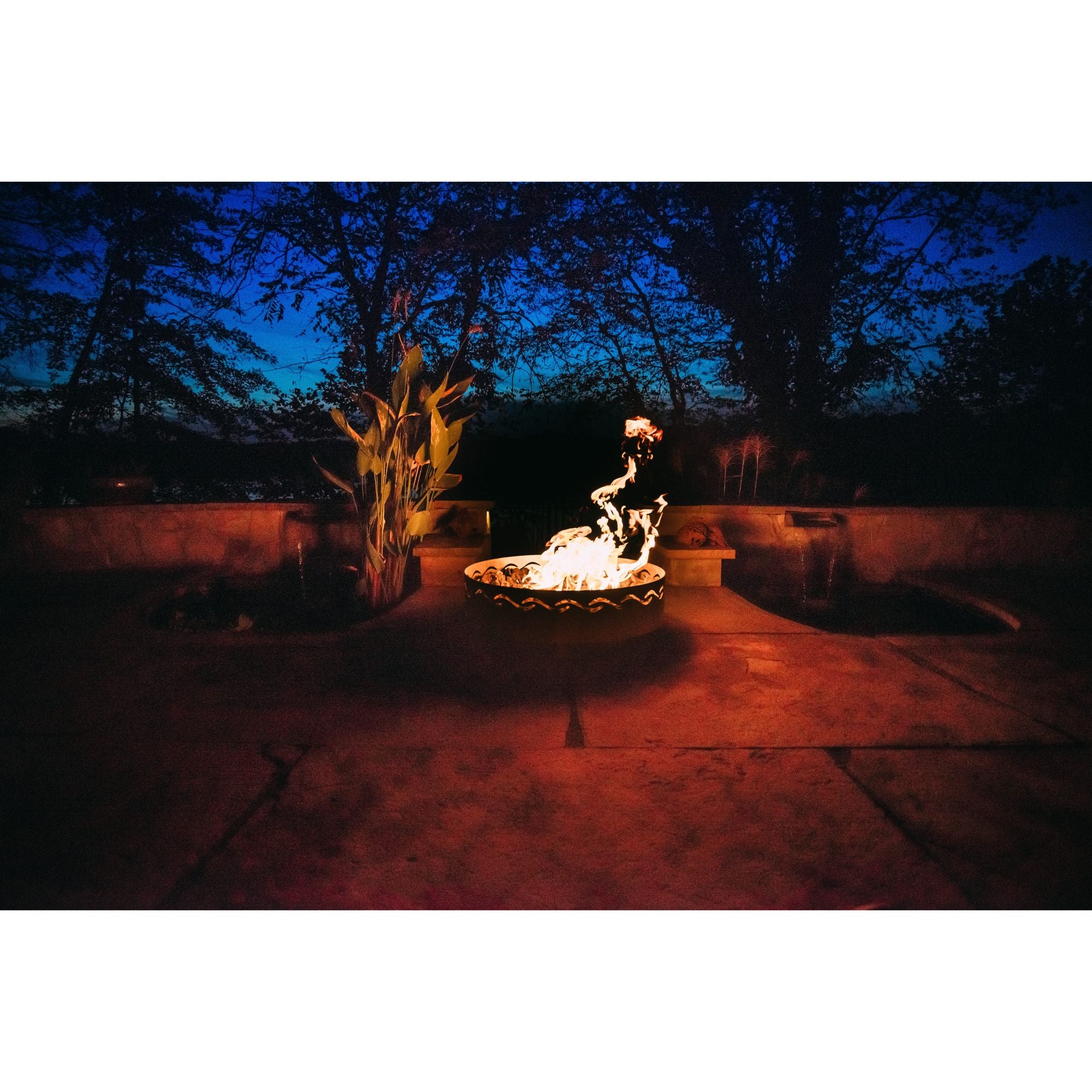 Fire pit in a backyard at night with trees in the background