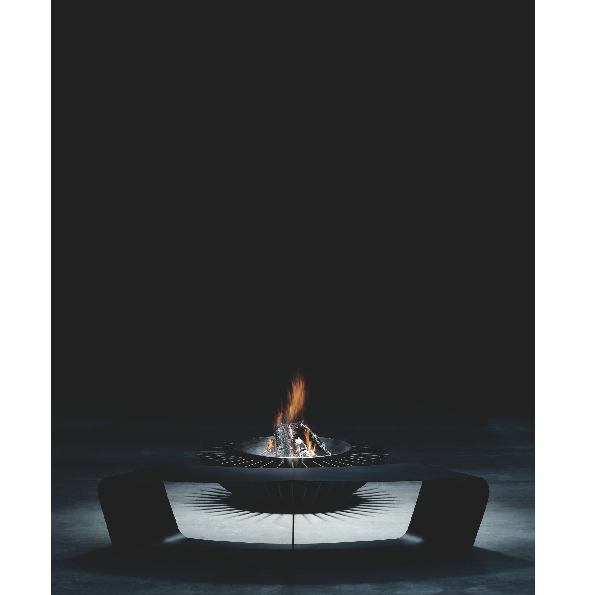 Modern outdoor fire pit with flames burning in a dark setting