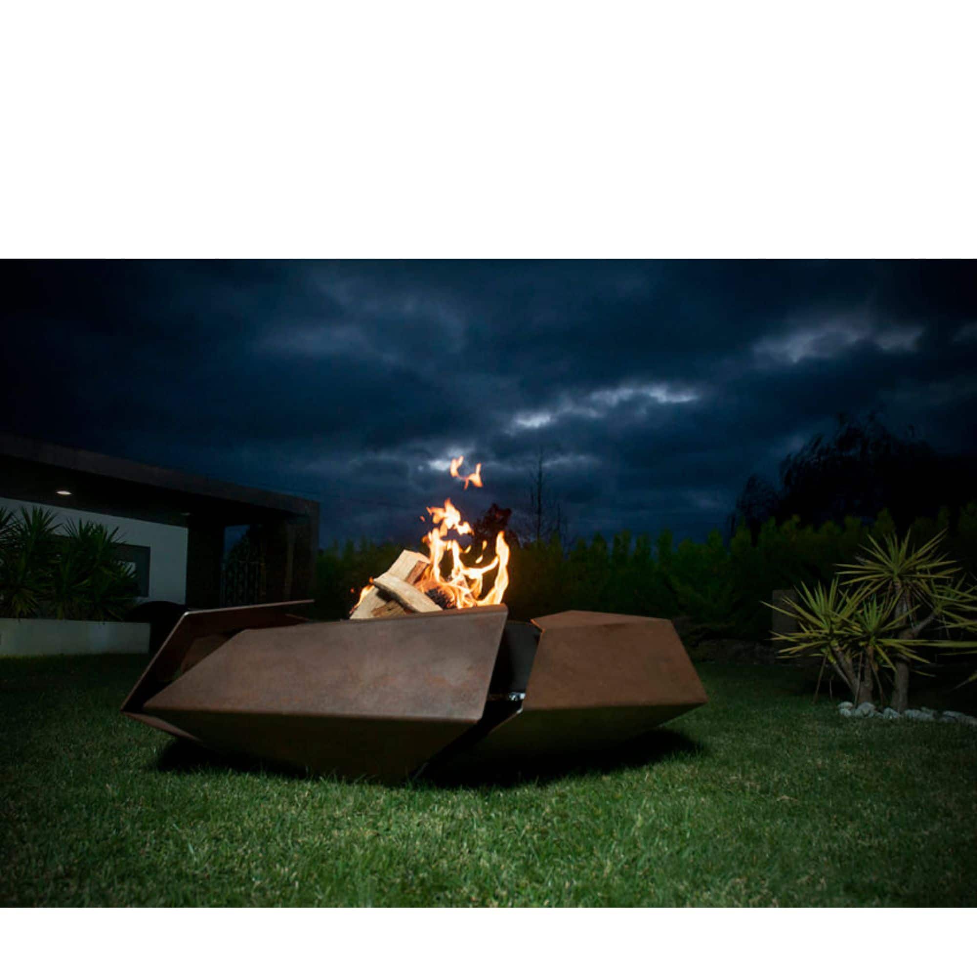 firepit with flames standing on grass in the evening