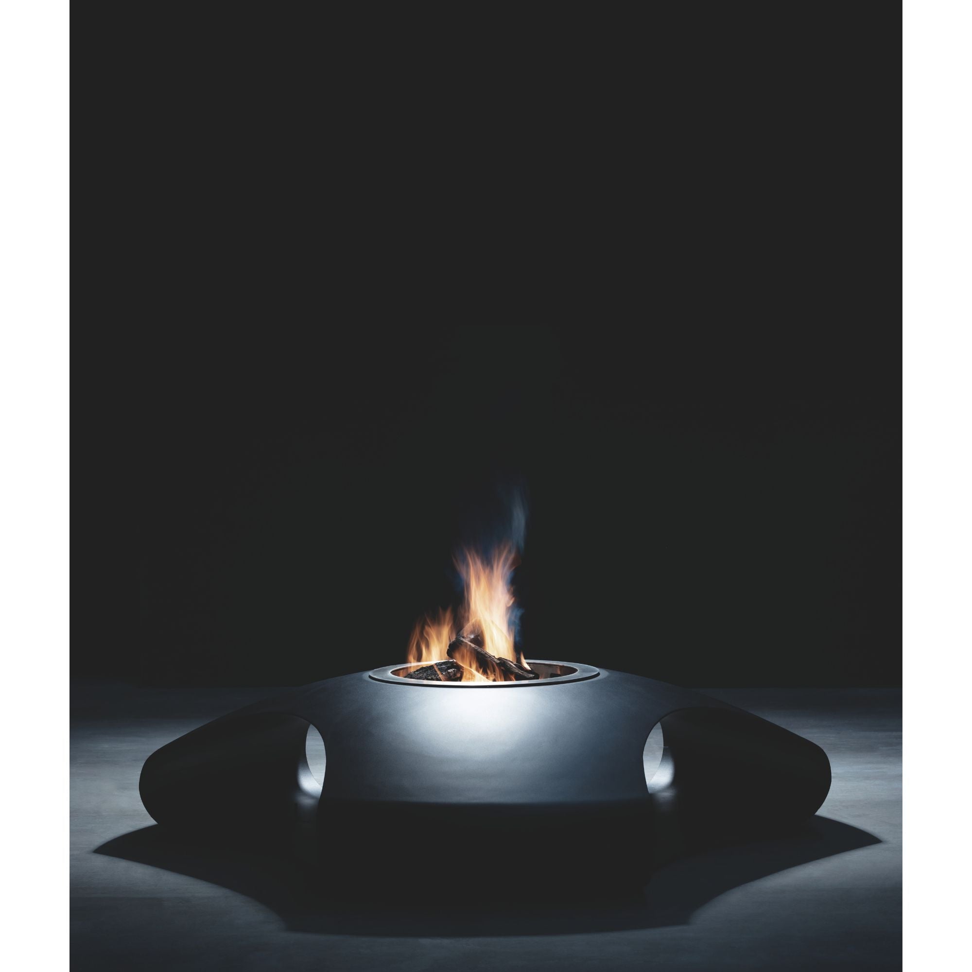 Modern outdoor fire pit with flames and logs on a dark background