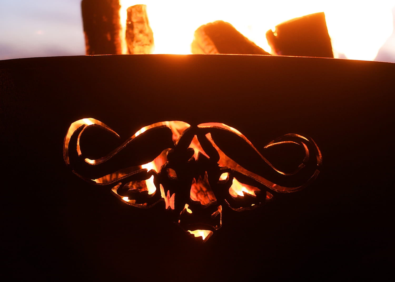 Metal fire pit with decorative design in front of a fire