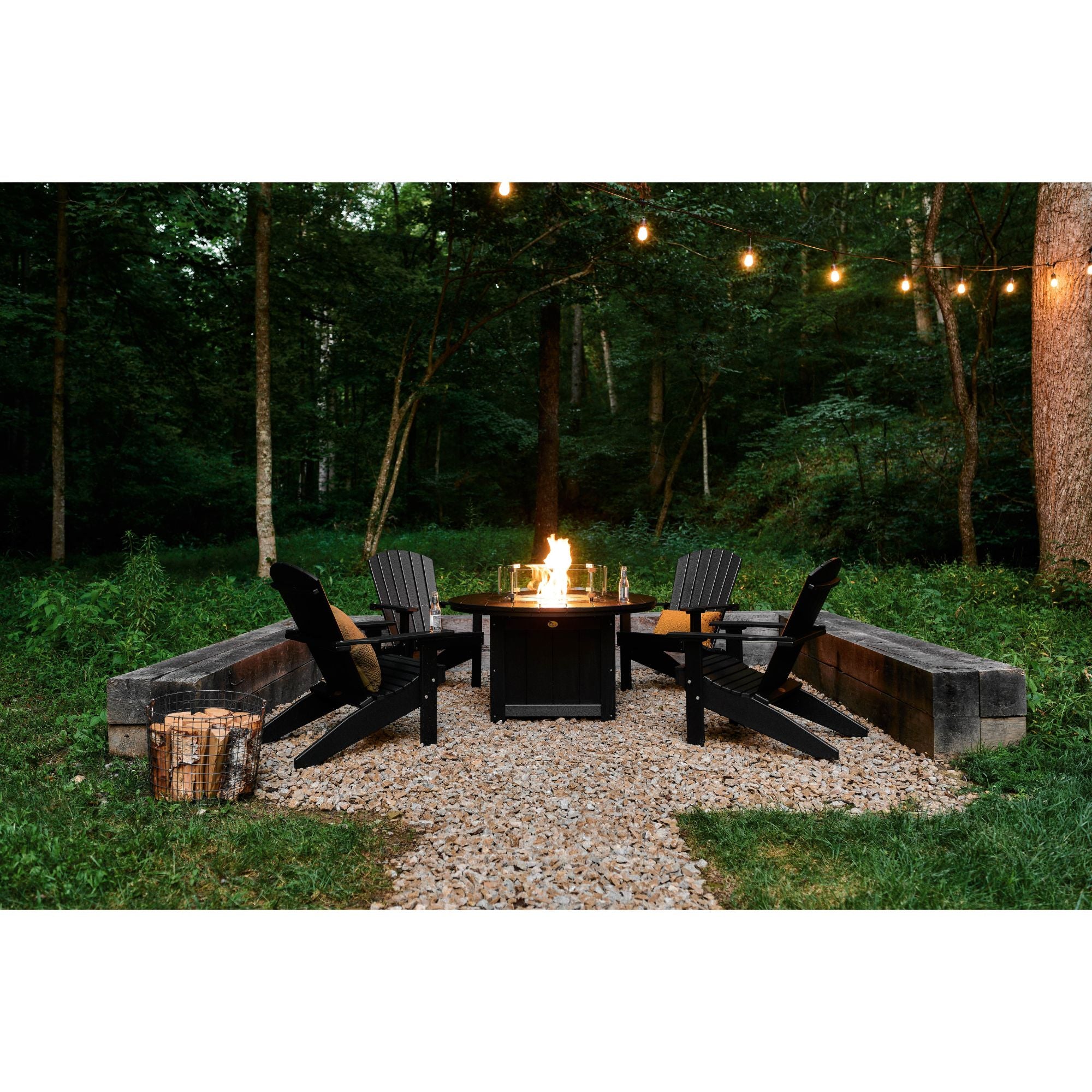 Outdoor fire pit area with chairs and string lights in a forest setting