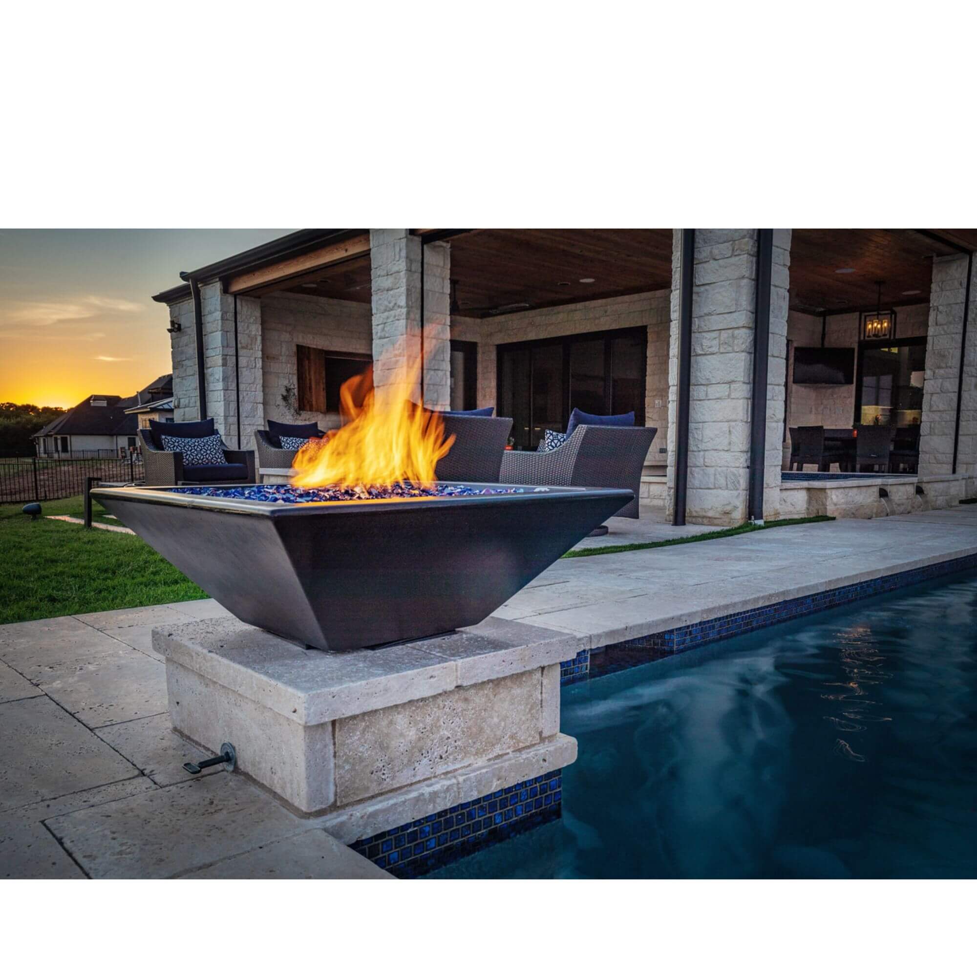 Outdoor fire pit with flames by a pool at sunset