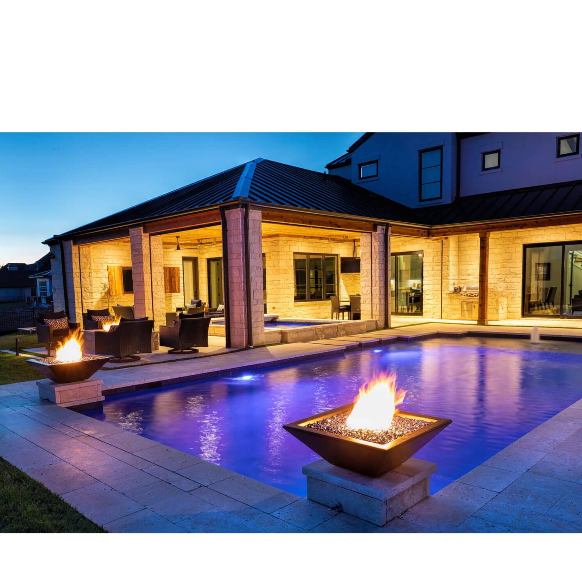 Modern house with a pool and fire pits at dusk