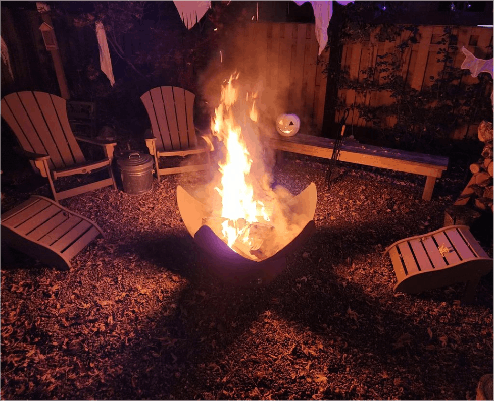 Fire pit surrounded by Adirondack chairs in a dimly lit outdoor setting