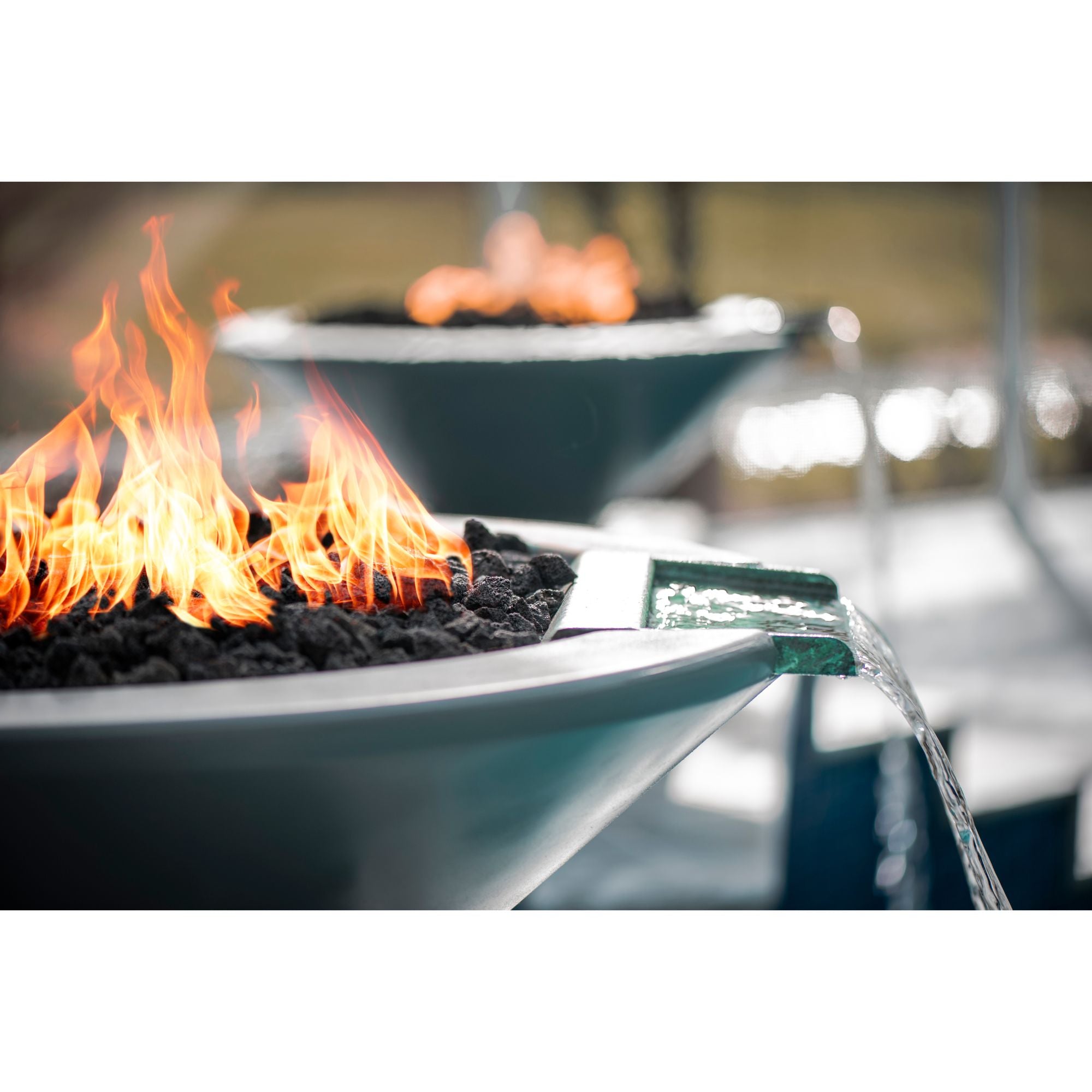 fire and water bowl with flames by a pool, with running water from the bowls water scupper